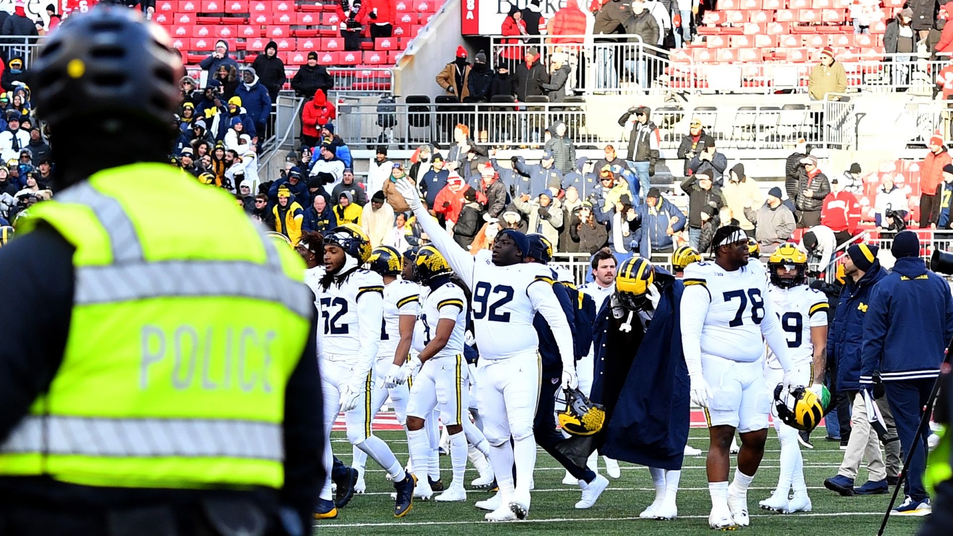 The Wolverines players celebrate as a police officer watches on in the aftermath of the Ohio State vs Michigan game in 2024