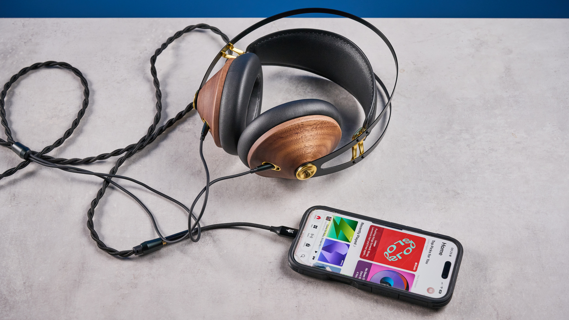 אוזניות ה-meze 99 classics דור 2 עם גימורי אגוז ונגיעות זהב על רקע המדריך הכחול של Tom's