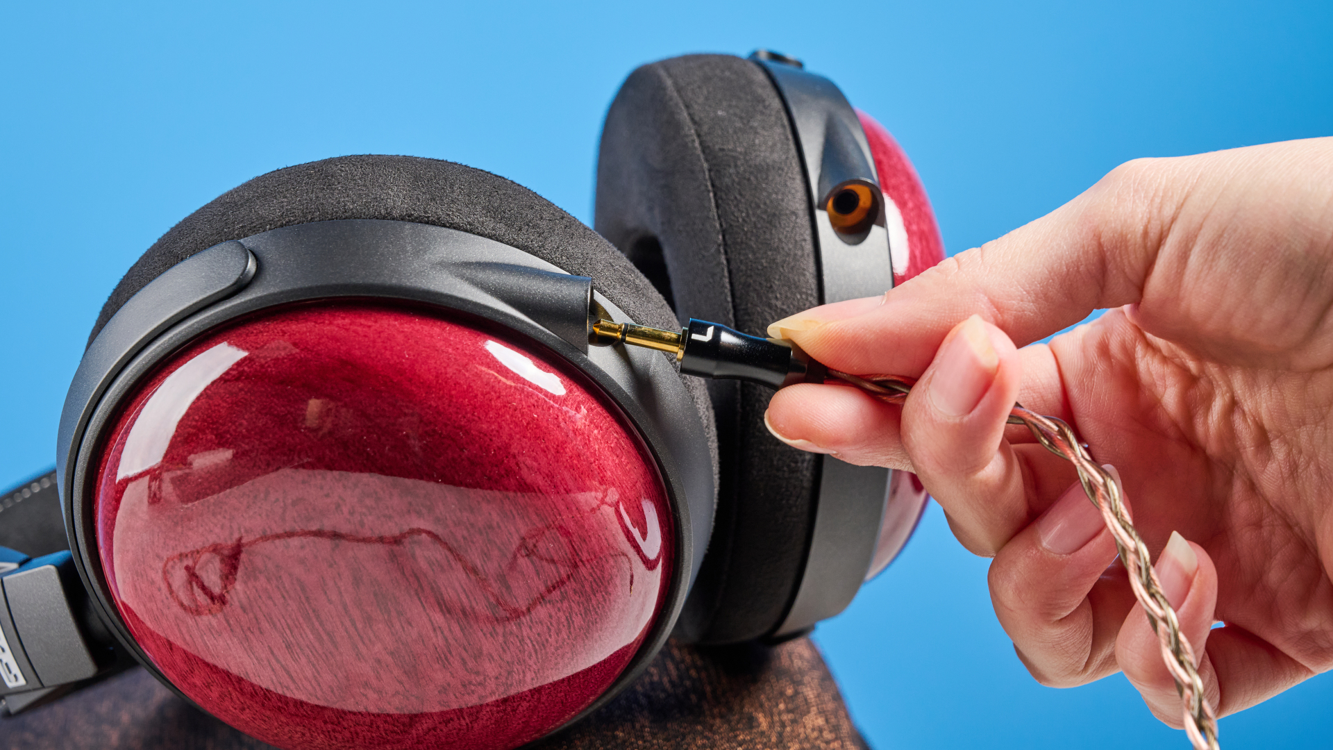 האוזניות החוטיות של fiio ft13 עם כוסות עץ וכבל נחושת שצולמו על רקע כחול