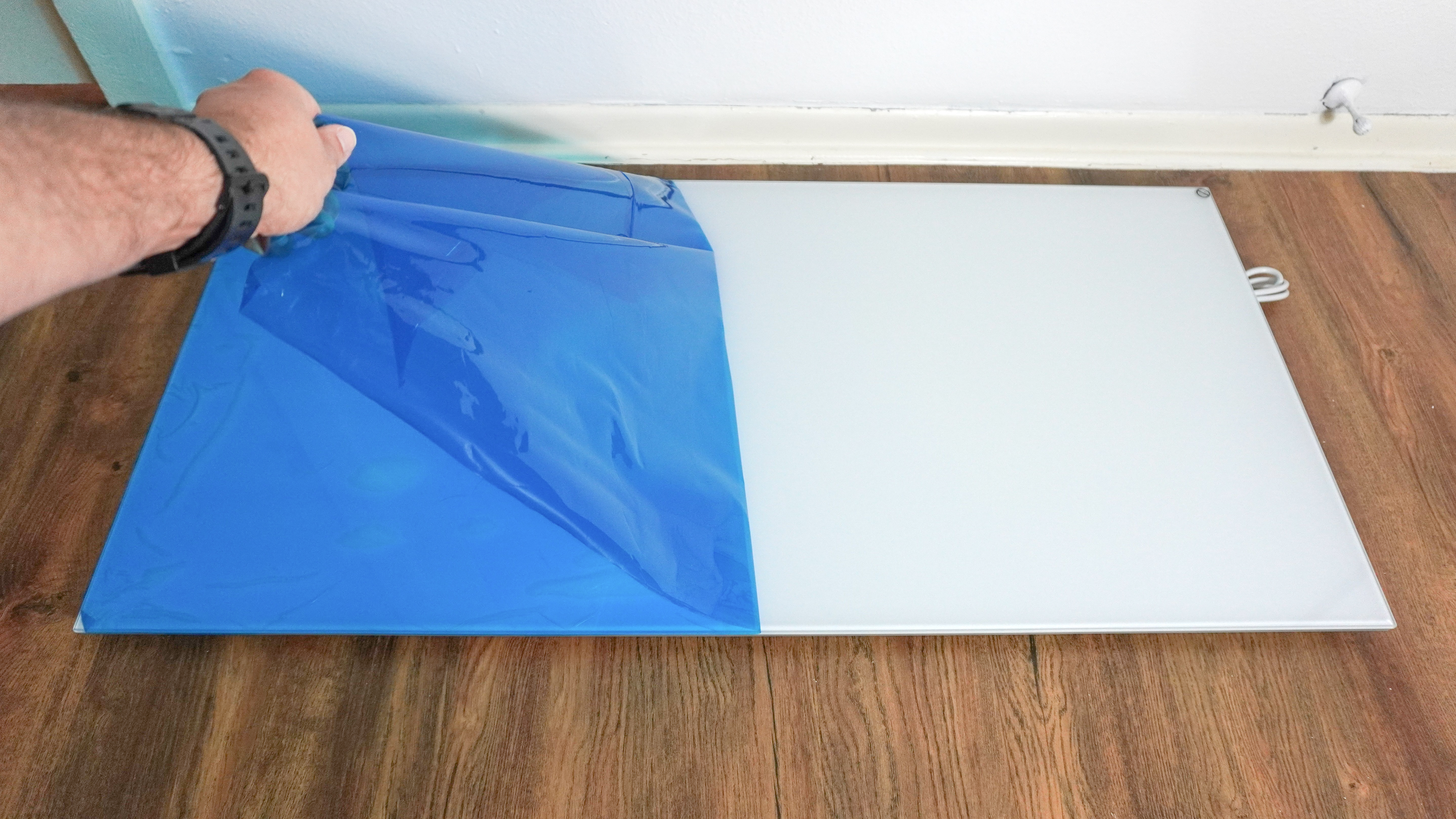 אדם מקלף את הסרט המגן המכסה את תנור האינפרא אדום Boldr Kelvin כדי לחשוף את משטח הזכוכית שלו מתחת