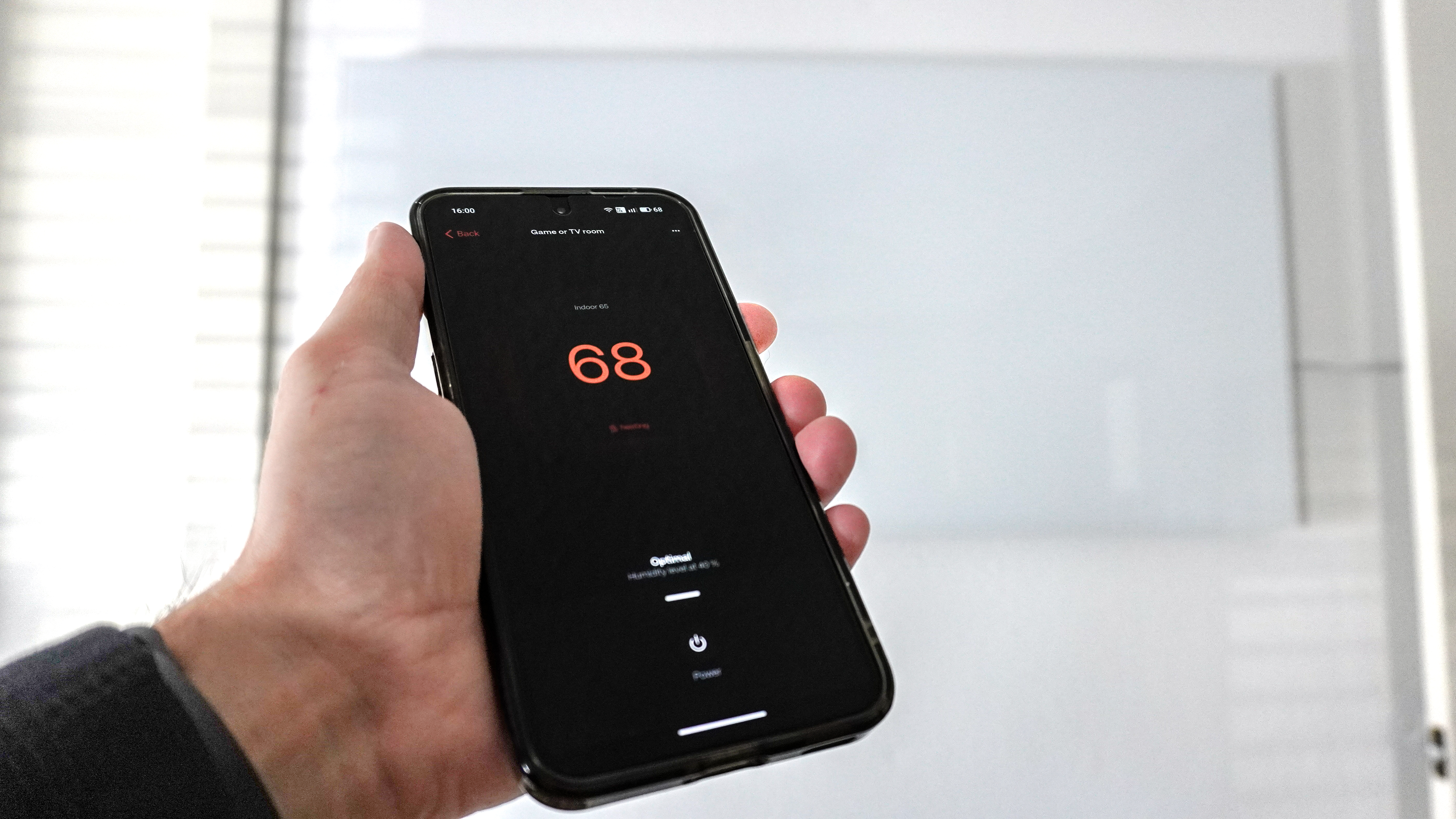 אדם המשתמש באפליקציית Boldr כדי לשלוט במחמם האינפרא אדום החכם התלוי על הקיר