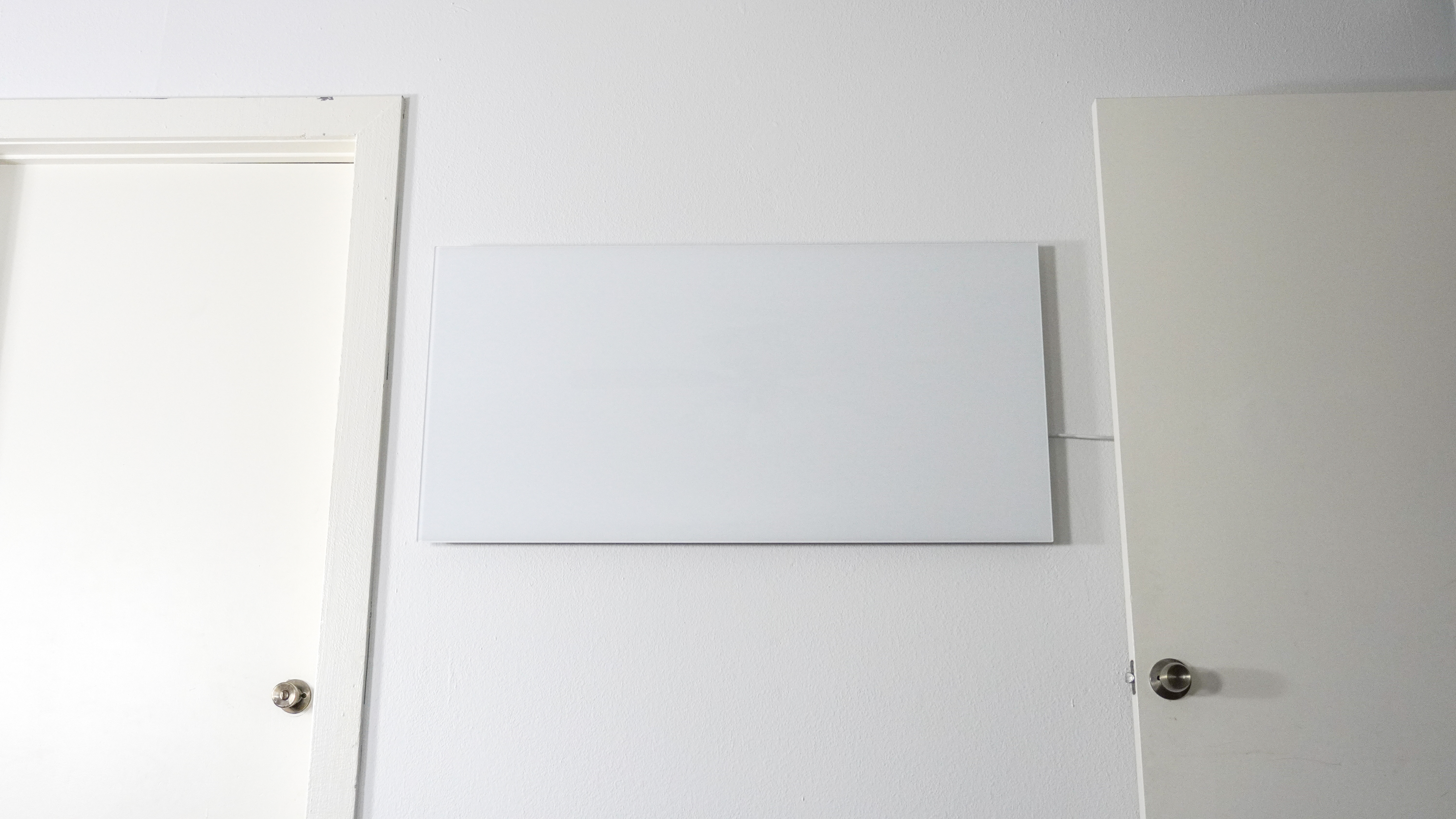 צילום רחב של תנור חימום אינפרא אדום של Boldr Kelvin המותקן על קיר בין שתי דלתות