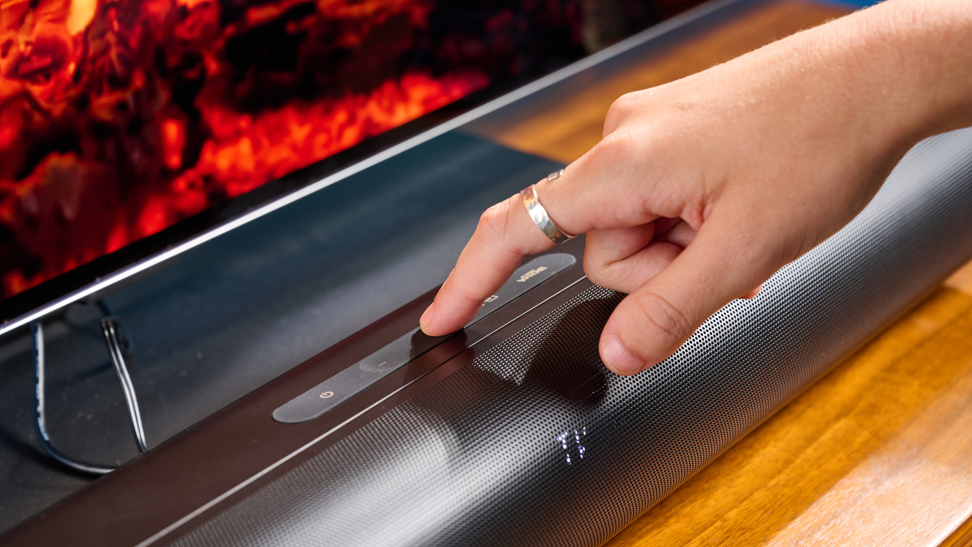 סרגל הסאונד והסאבוופר היצירתי של stage pro, מערכת קולנוע ביתי בתקציב סופר-תקציבי עם 2.1 ערוצים ושלט רחוק מצולם על מעמד טלוויזיה מעץ עם טלוויזיה מאחור