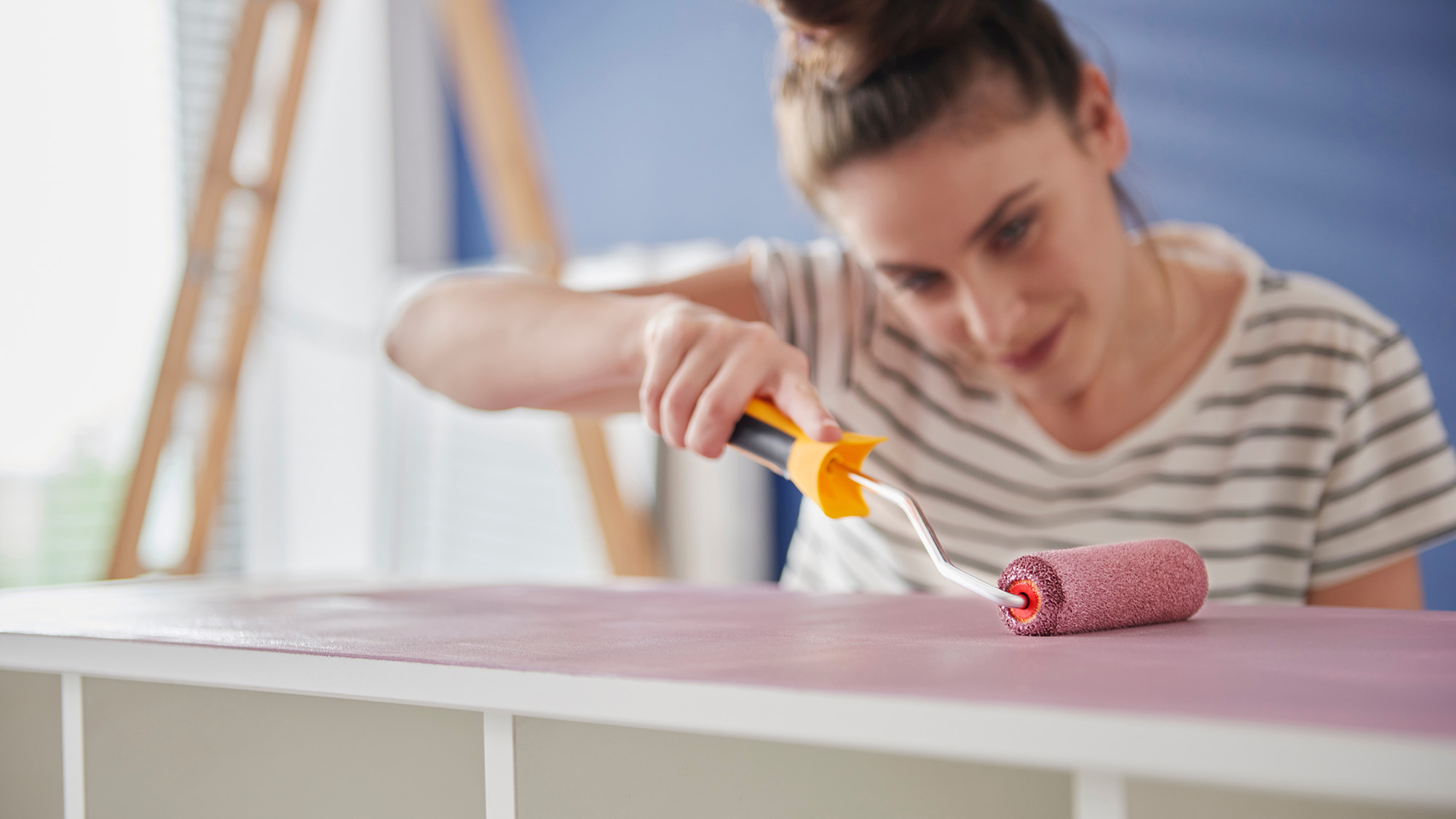 אישה מציירת יחידת מדפים עם רולר