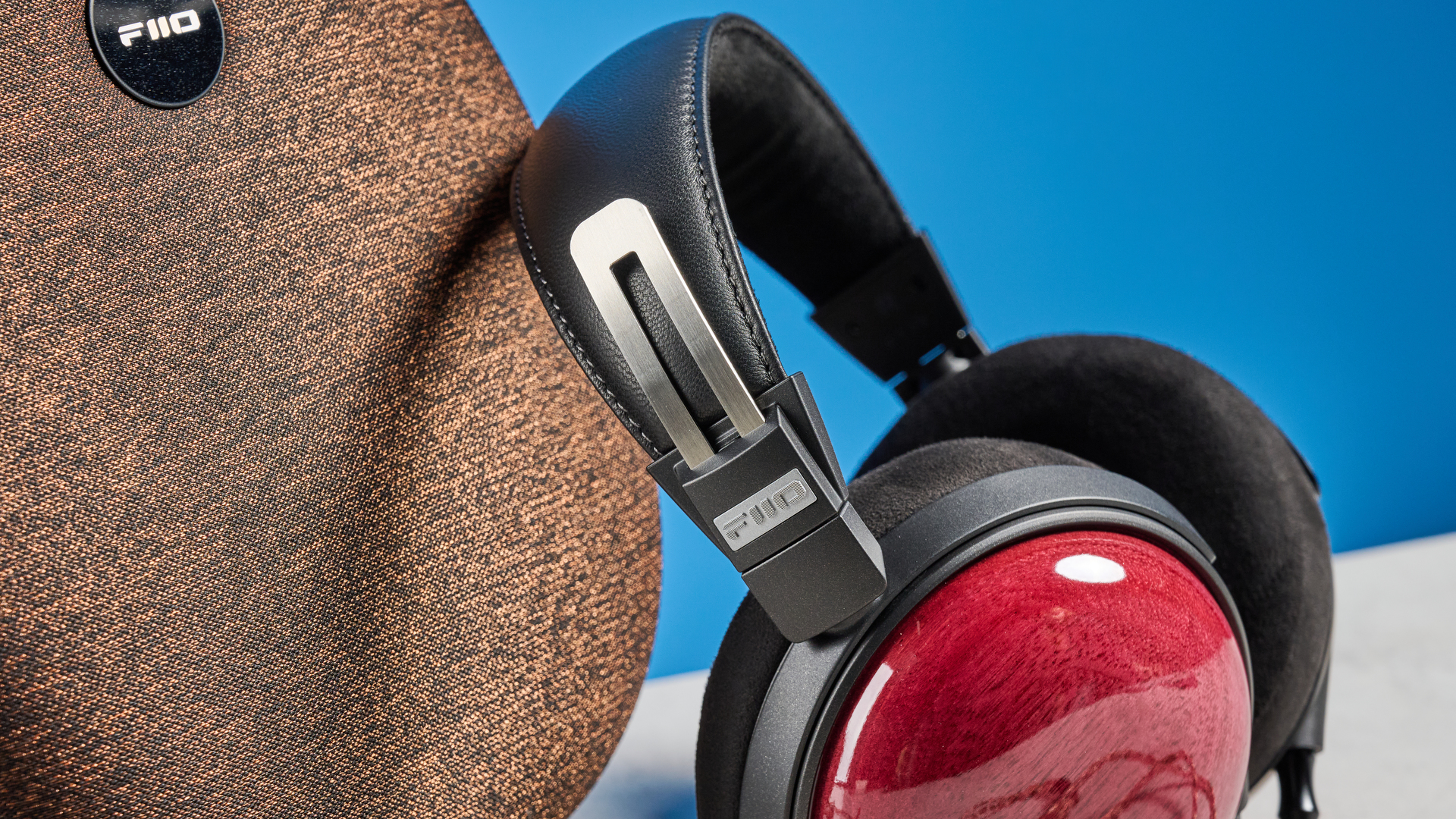 האוזניות החוטיות של fiio ft13 עם כוסות עץ וכבל נחושת שצולמו על רקע כחול