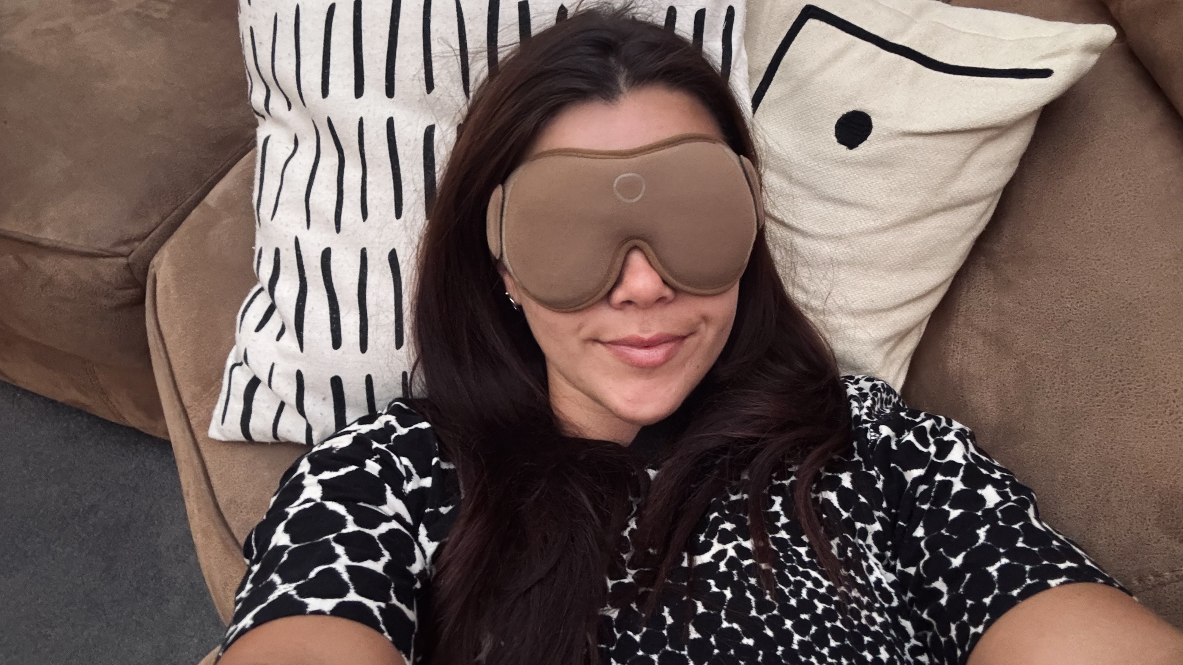 ילדה לובשת חולצה שחורה ולבן לובשת את מסכת השינה SOMO בז' שוכבת על הספה לנפוצ'ינו