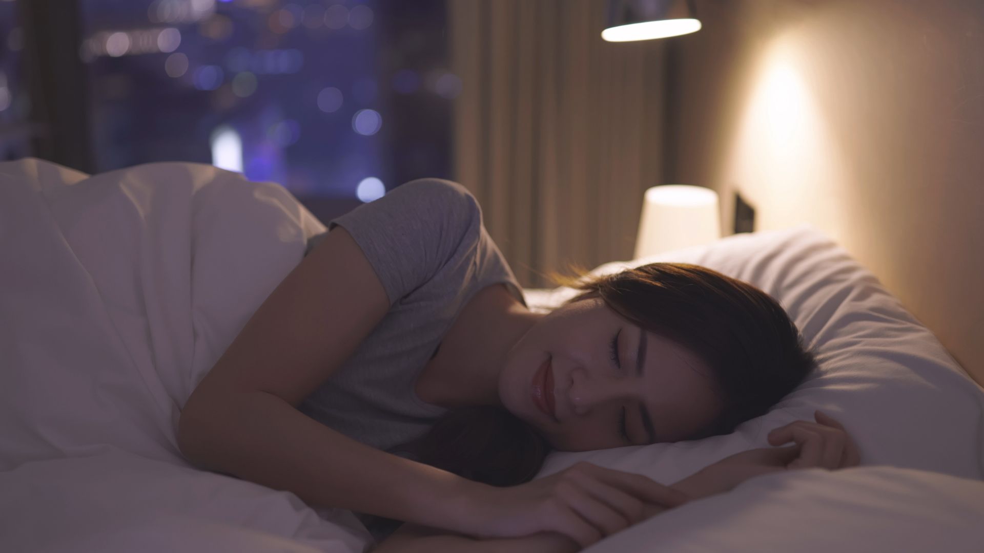 אישה שוכבת במיטה על צדה בלילה, נראה כאילו זה עתה נרדמה.