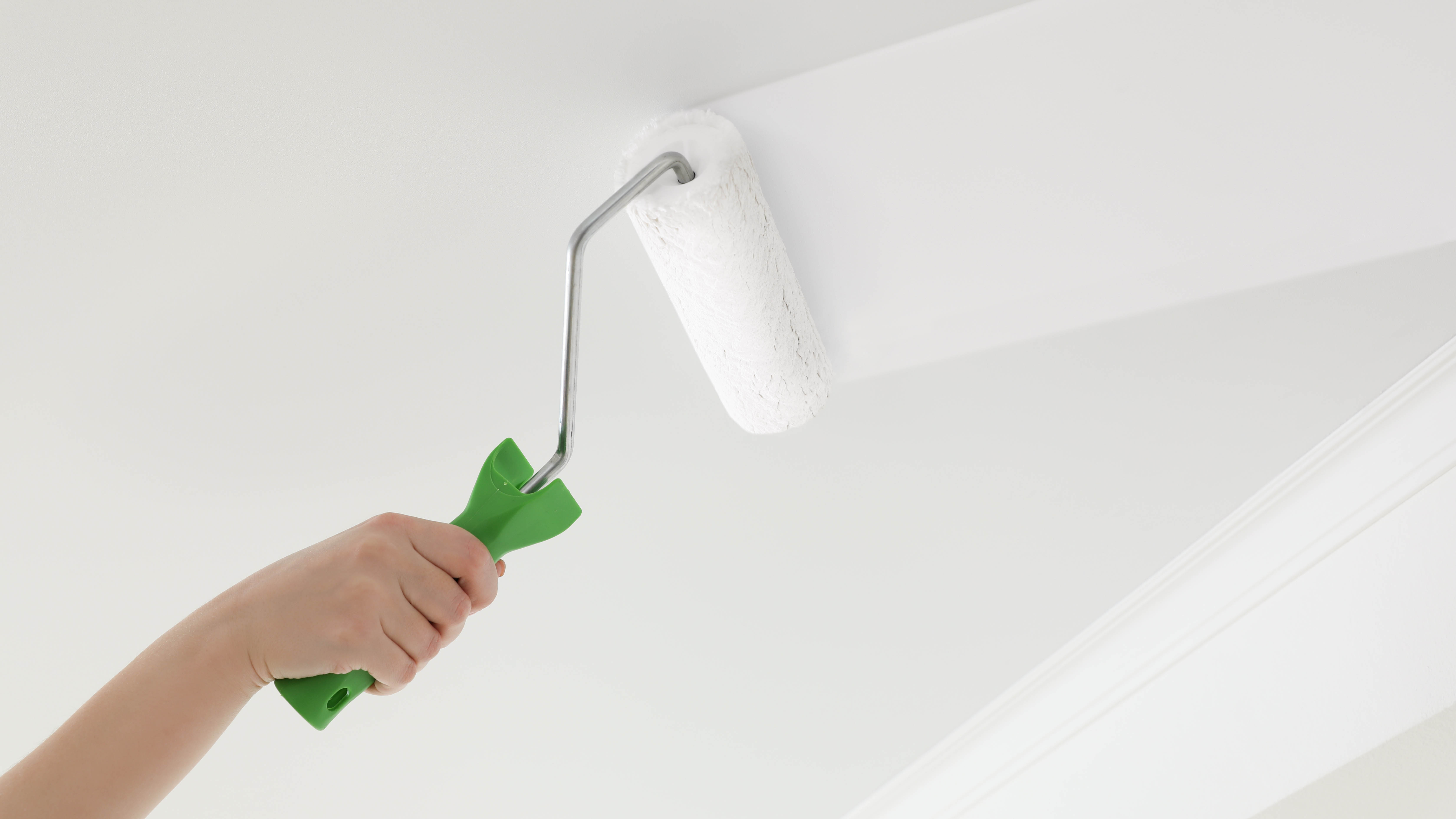 רולר צובע צבע לבן על תקרה