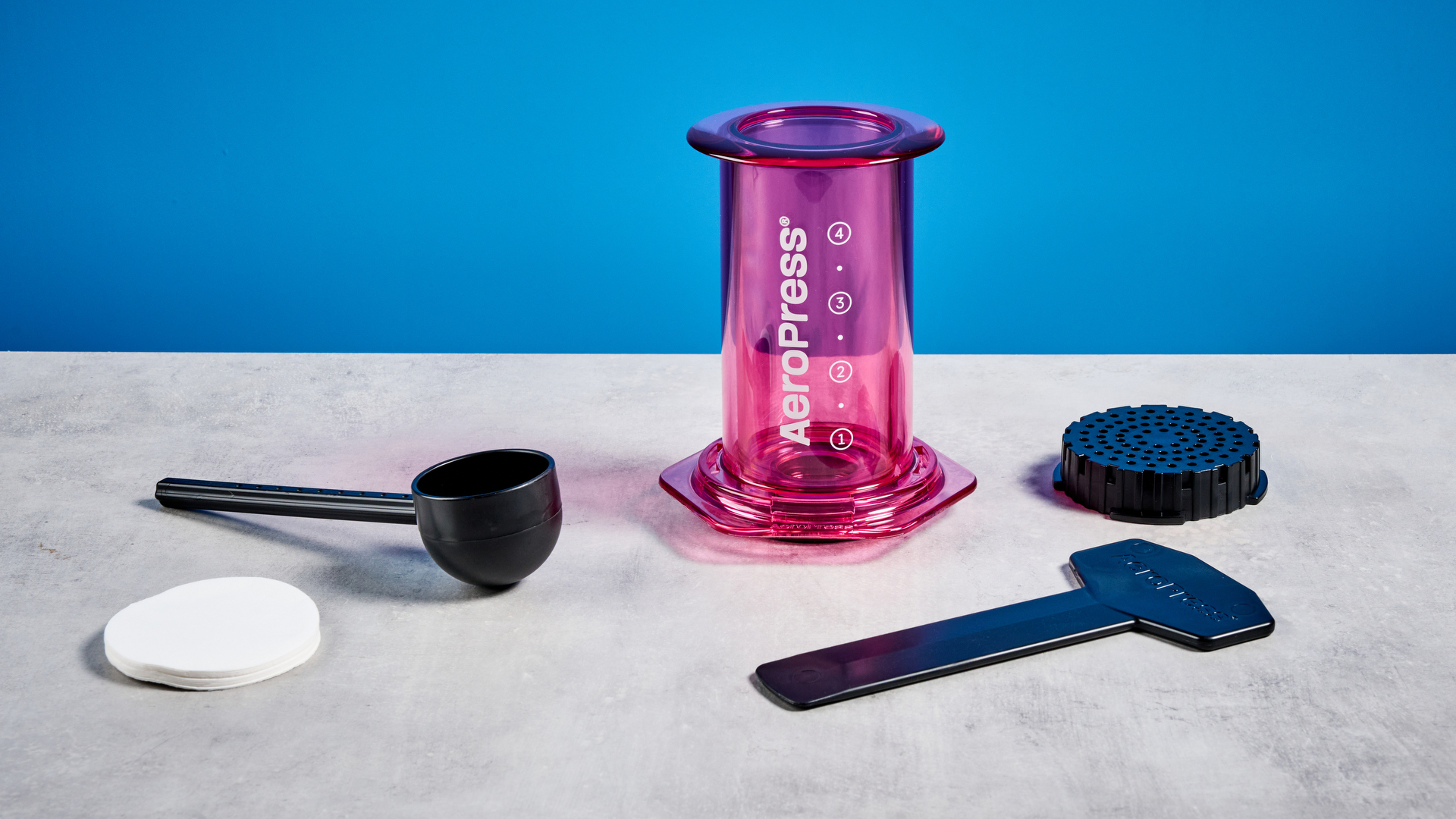 צבע ה-aeropress ברור בוורוד שצולם על רקע המדריך הכחול