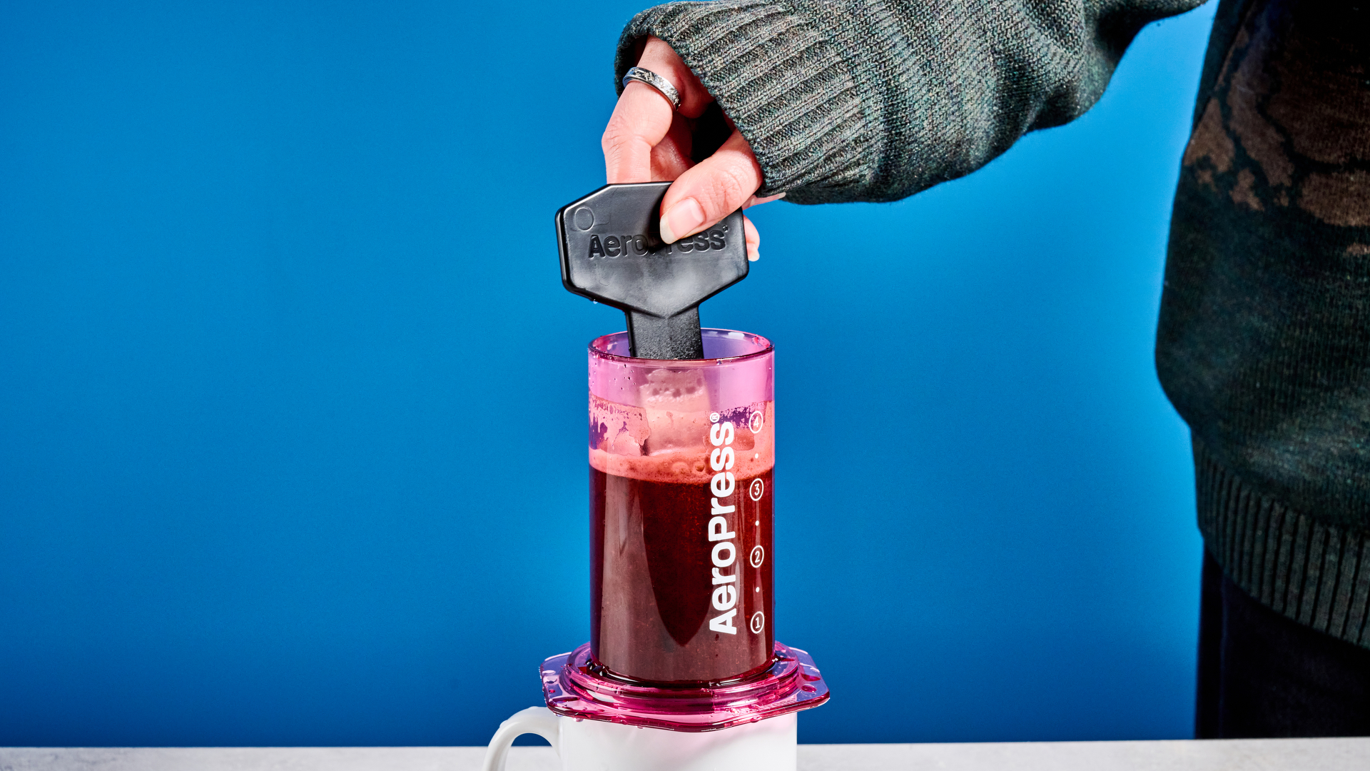 צבע ה-aeropress ברור בוורוד שצולם על רקע המדריך הכחול