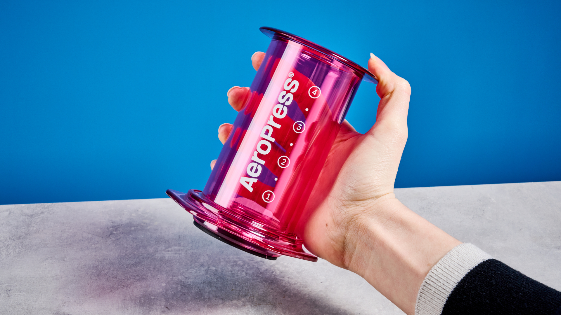 צבע ה-aeropress ברור בוורוד שצולם על רקע המדריך הכחול