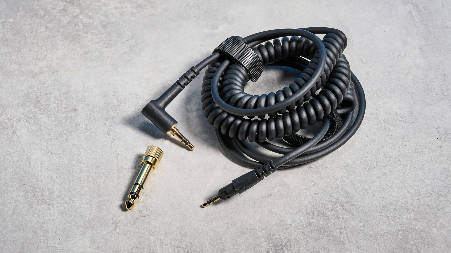 אוזניות DJ 300 Pro X של beyerdynamic בשחור מציגות את כוסות האוזניים, תיק הנשיאה ואפשרויות הקישוריות שלהן שצולמו על רקע המדריך הכחול של טום