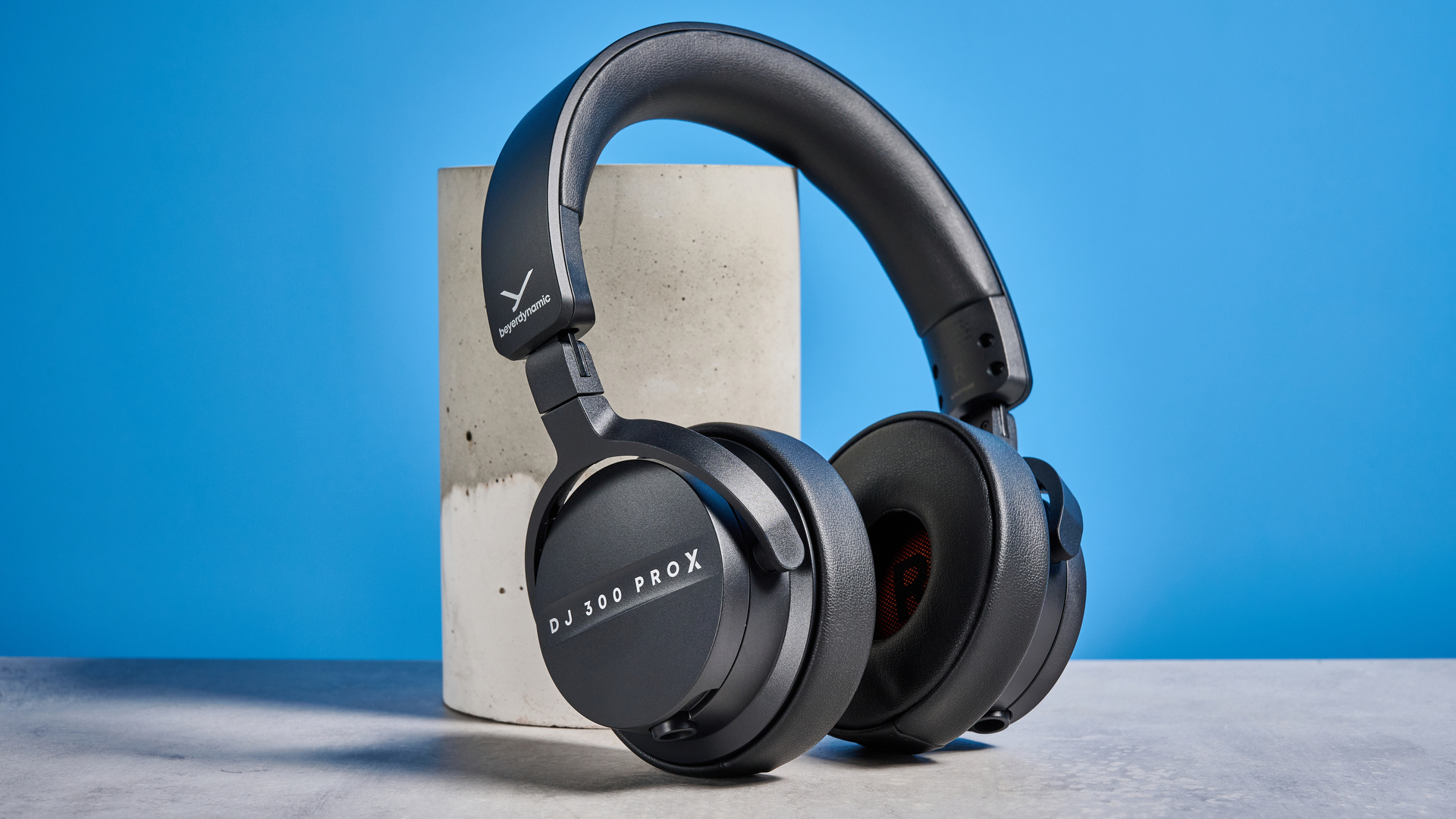 אוזניות DJ 300 Pro X של beyerdynamic בשחור מציגות את כוסות האוזניים, תיק הנשיאה ואפשרויות הקישוריות שלהן שצולמו על רקע המדריך הכחול של טום