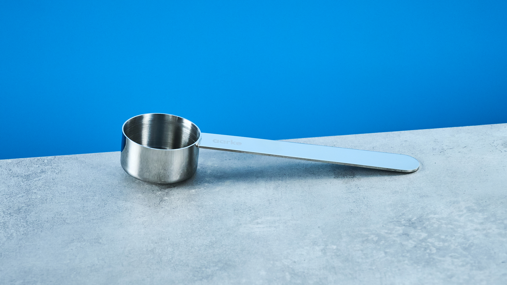 בית הבד הצרפתי של ארקה בצבע כסף מראה את מערכת מסנן העיתונות הצרפתית, מכסה, פיה ובפנים מצולמים על רקע המדריך הכחול של טום