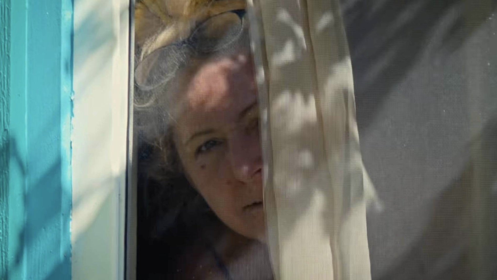 Old woman looking out from behind curtain