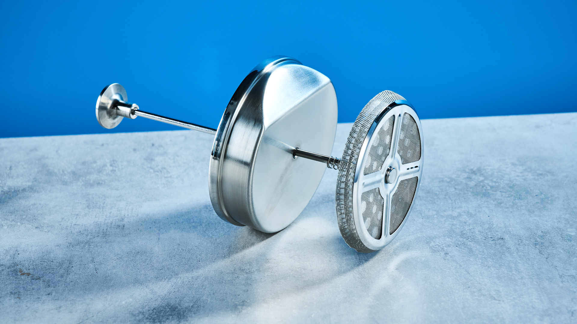 בית הבד הצרפתי של ארקה בצבע כסף מראה את מערכת מסנן העיתונות הצרפתית, מכסה, פיה ובפנים מצולמים על רקע המדריך הכחול של טום