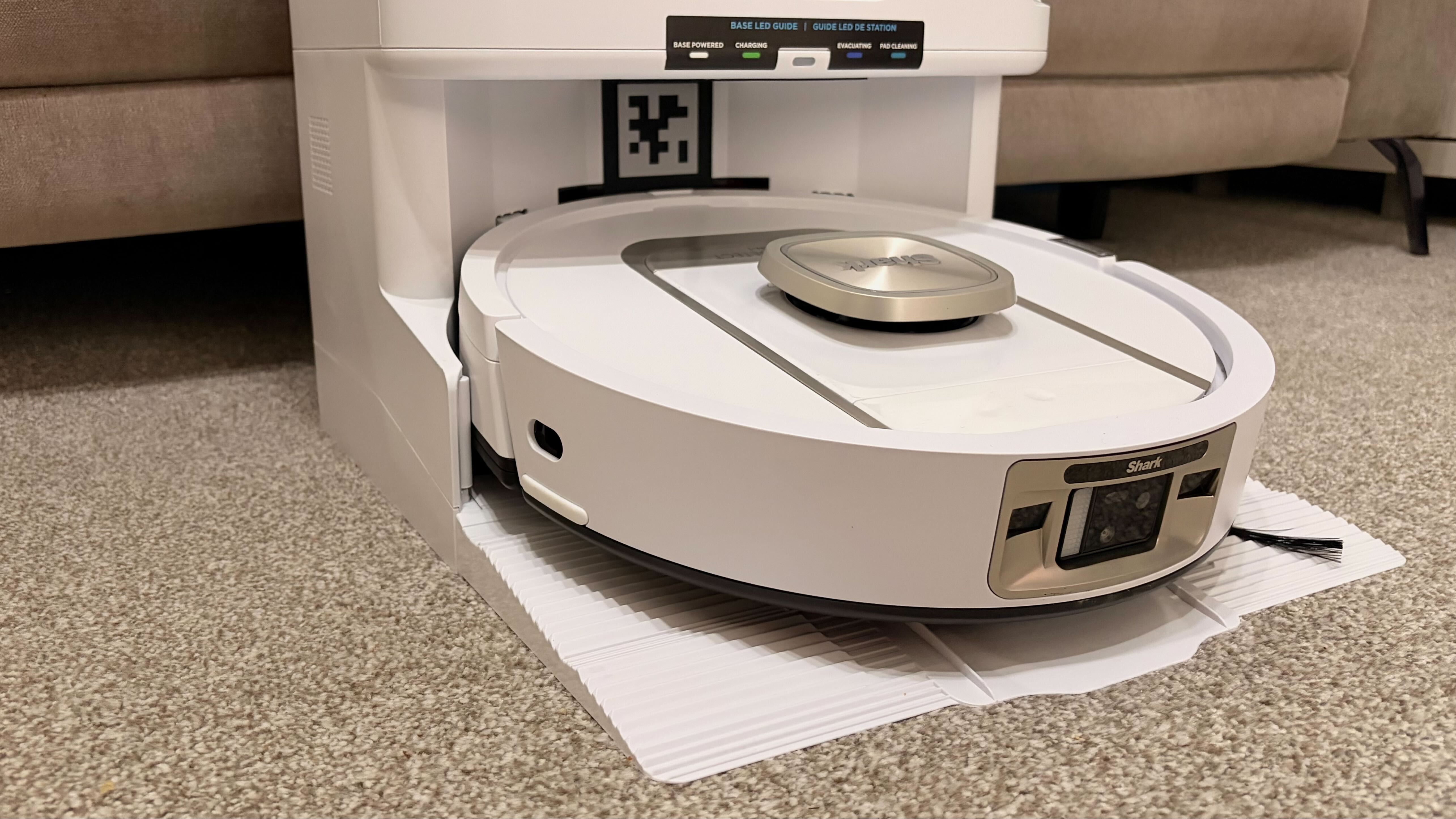 Shark PowerDetect 2-in-1 ThermaCharged NeverTouch צולם על שטיח עם תחנת עגינה