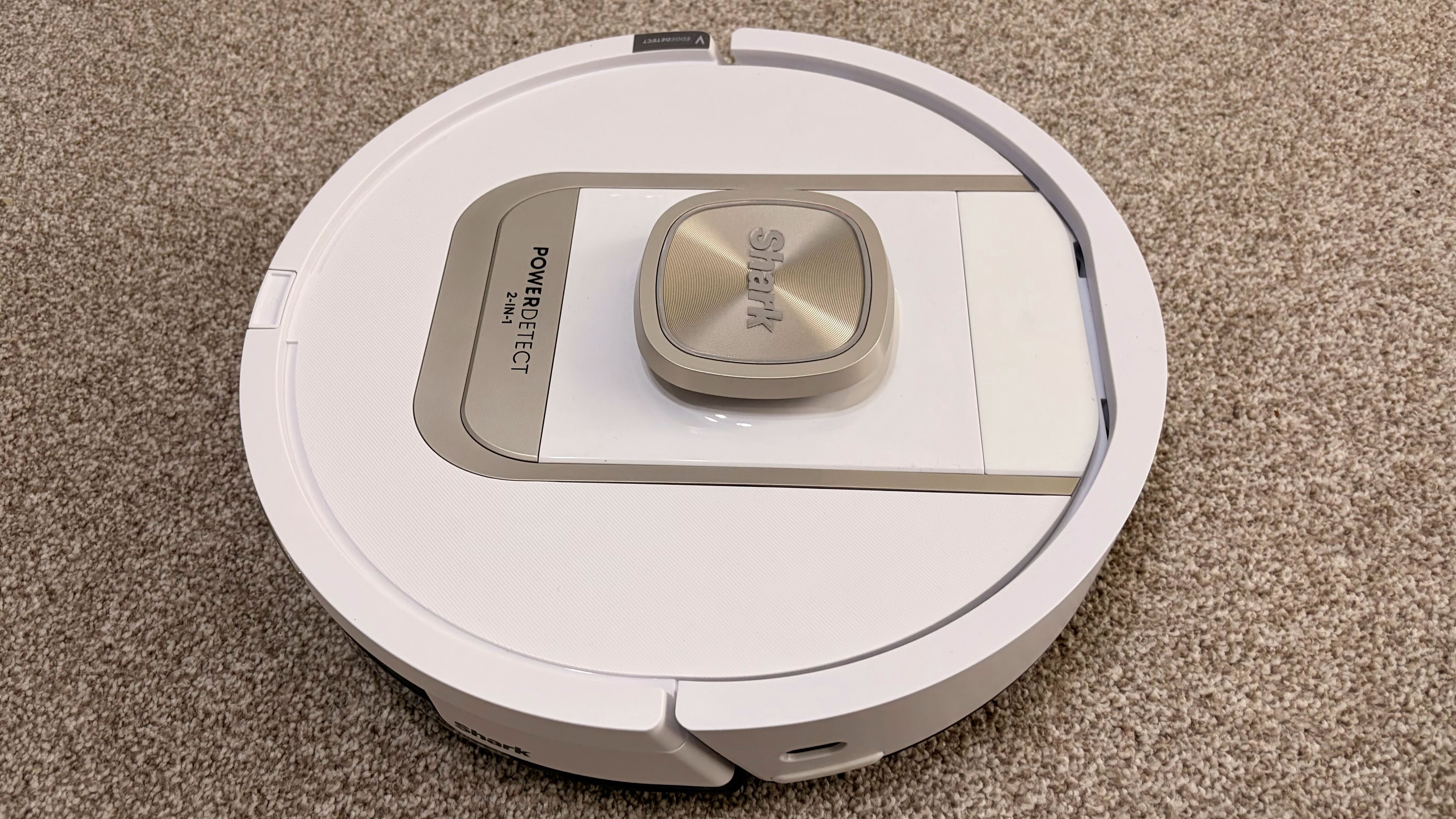 Shark PowerDetect 2-in-1 ThermaCharged NeverTouch צולם על שטיח עם תחנת עגינה