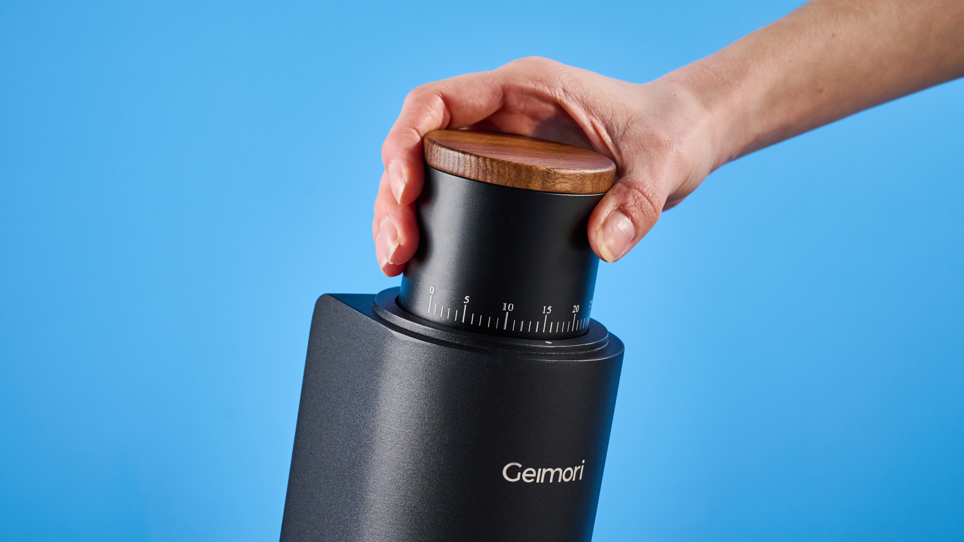 מטחנת הקפה של wirsh geimori gu38 בשחור עם מכסה קופר אגוז שצולמה על רקע המדריך הכחול של טום