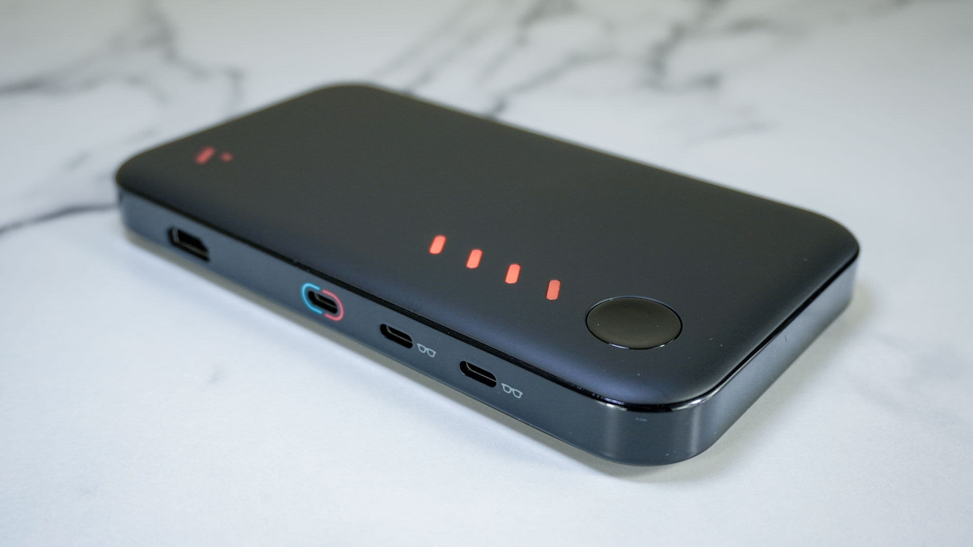 תחנת העגינה הניידת של Viture Pro על שולחן מציגה את היציאות שלו ואת נוריות חיווי הסוללה בחלק העליון של המכשיר