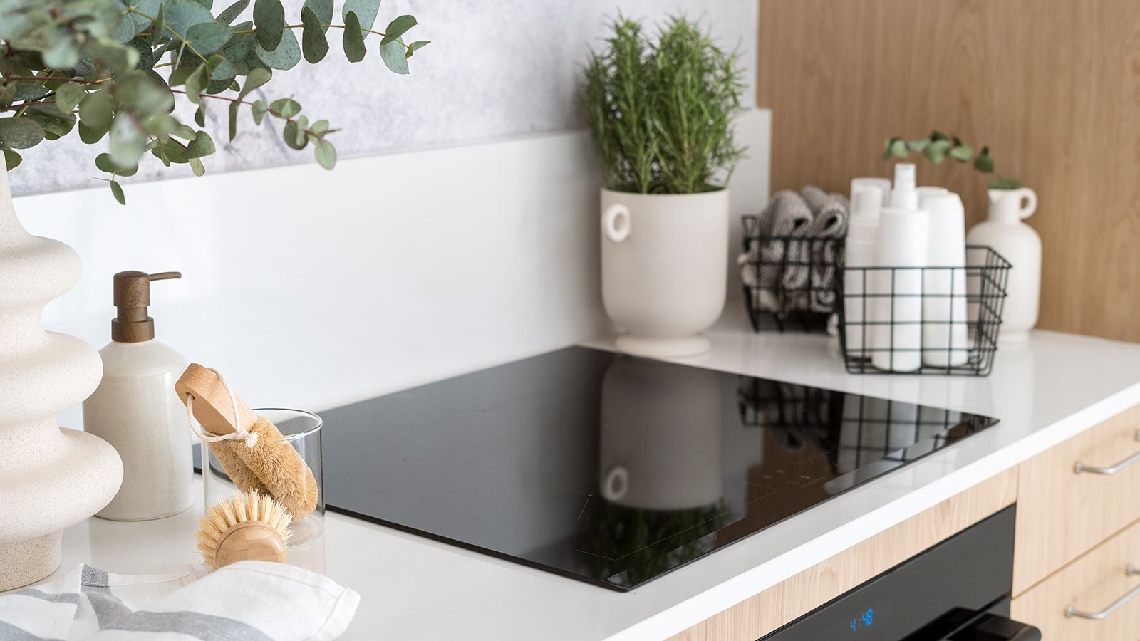 Induction cooktop in a white kitchen next to natural cleaning products