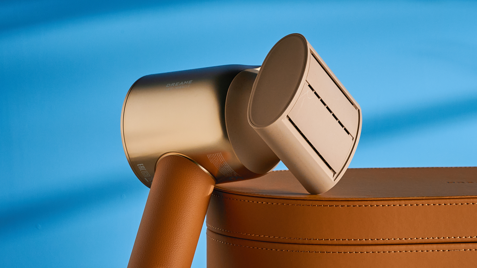 מייבש השיער dreame miracle pro בצבע זהב המציג את קופסת האחסון על רקע המדריך הכחול, עם ארבע חרירי החיבור כולל שתי פיות ייבוש, מפזר, והאיילוף המעופף