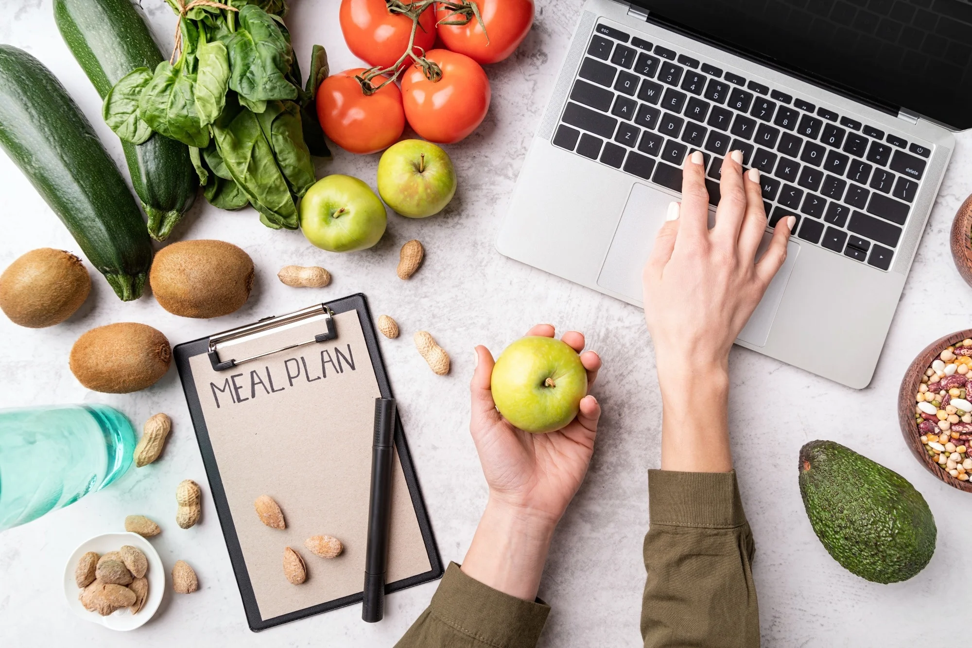 Woman workspace with healthy food. Female hands writing in the notepad words