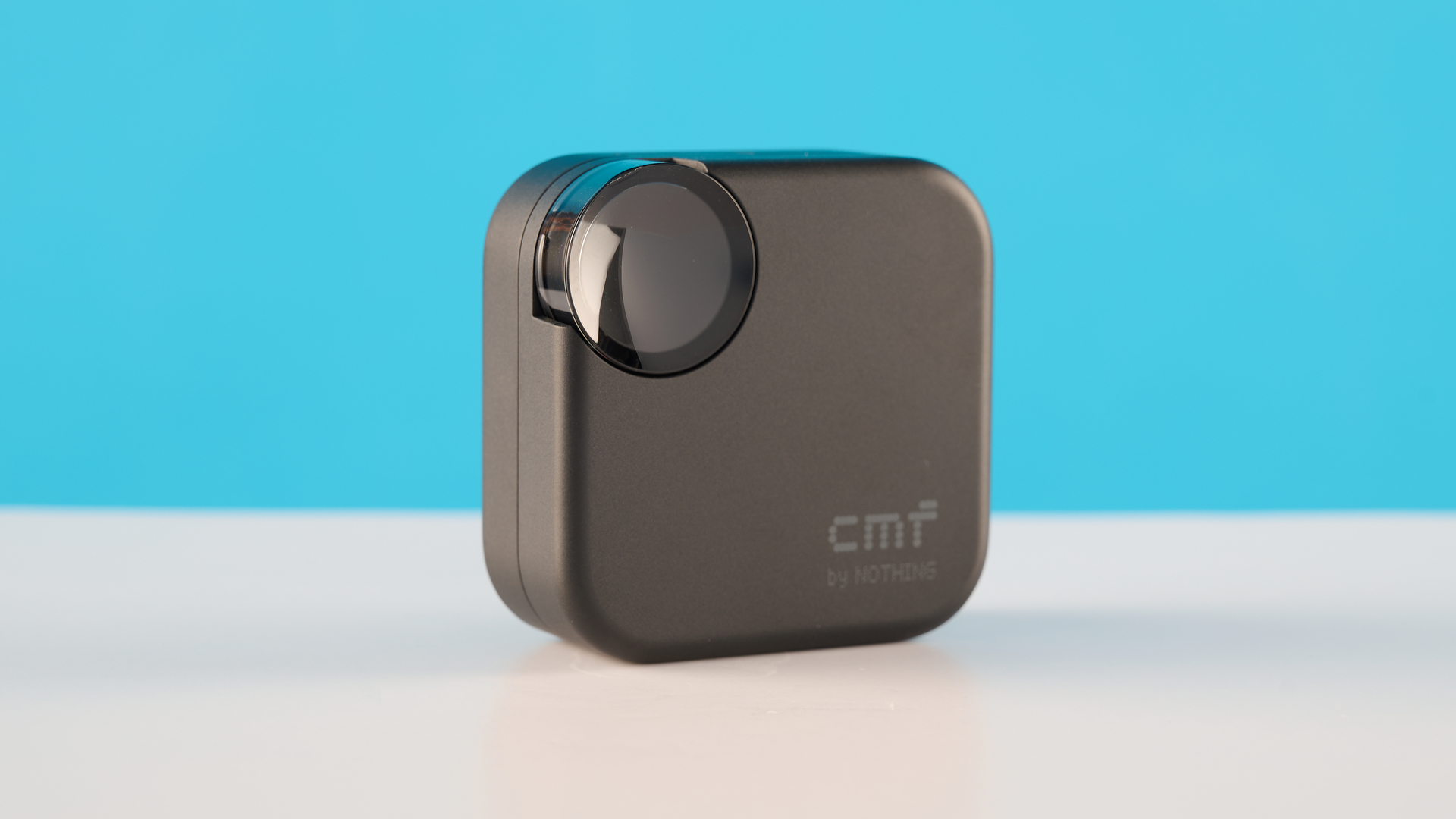 CMF Buds 2 בצילומי אפור כהה על שולחן אפור מול רקע כחול