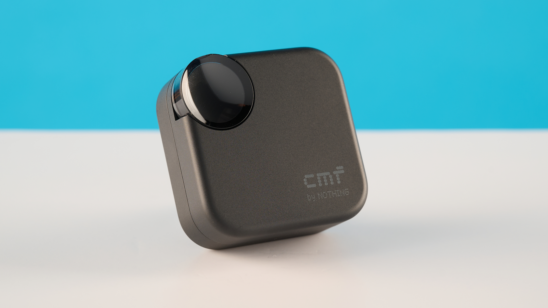 CMF Buds 2 בצילומי אפור כהה על שולחן אפור מול רקע כחול