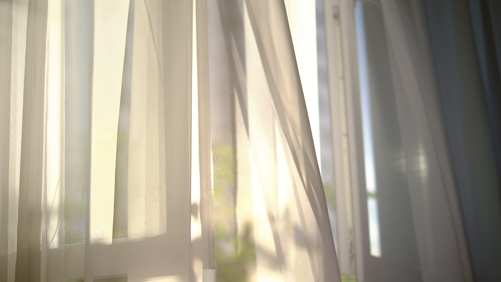 חלון פתוח עם וילונות קלים נושבים ברוח