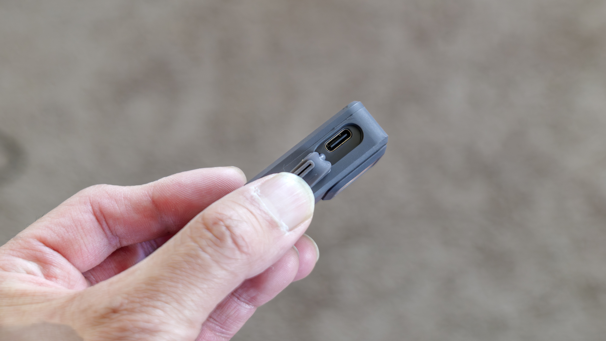 Pebblebee Halo מוחזק ביד עם תקריב של יציאת USB-C.