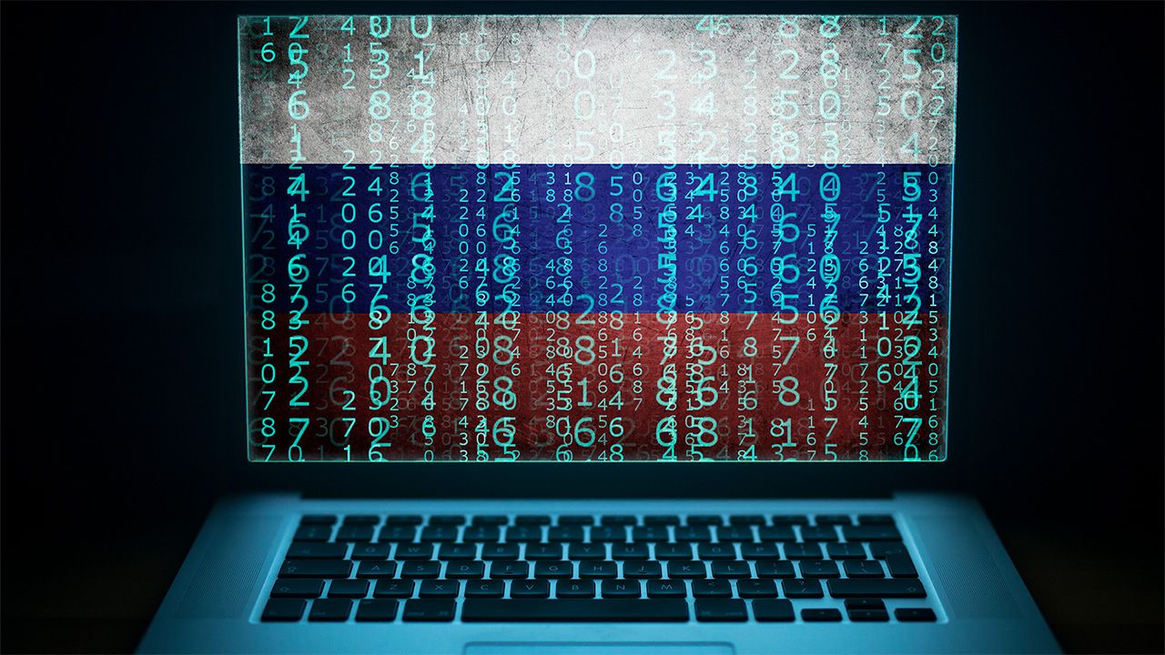 Computer with binary computer code and Russian flag on the screen