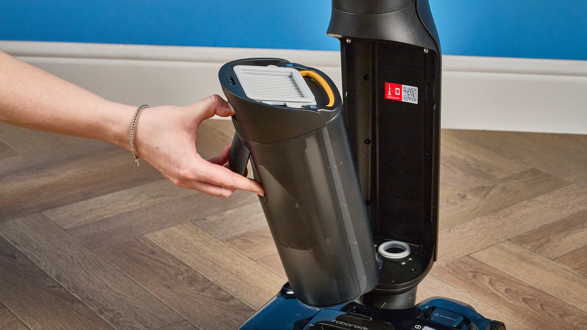 מיכל מים מלוכלך של ה-Roborock F25 ACE Pro שצולם על רצפת עץ חומה