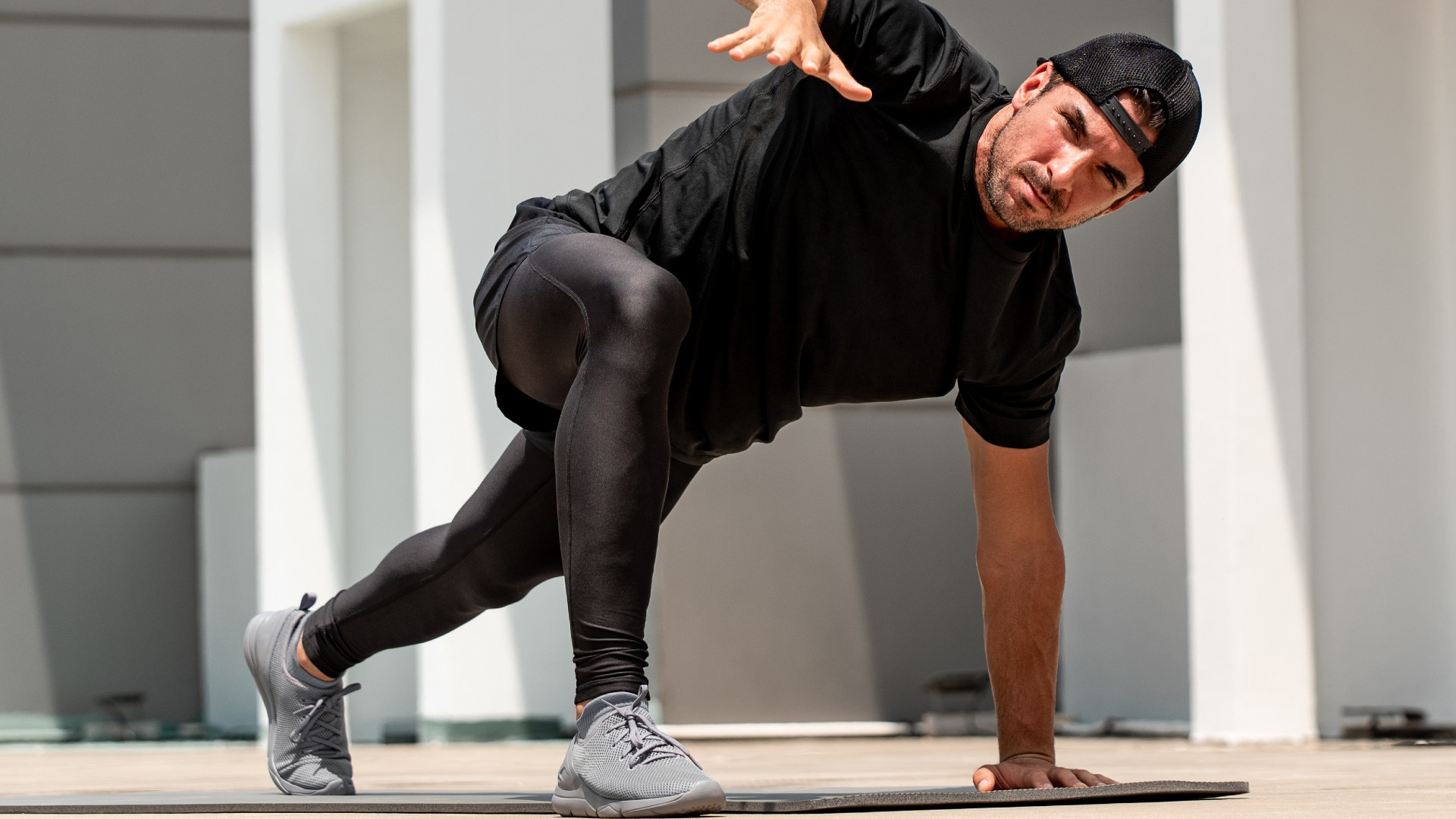 ספורטאי צעיר מתחמם עם התעמלות עכביש בחוץ בקומת הגג של הבניין