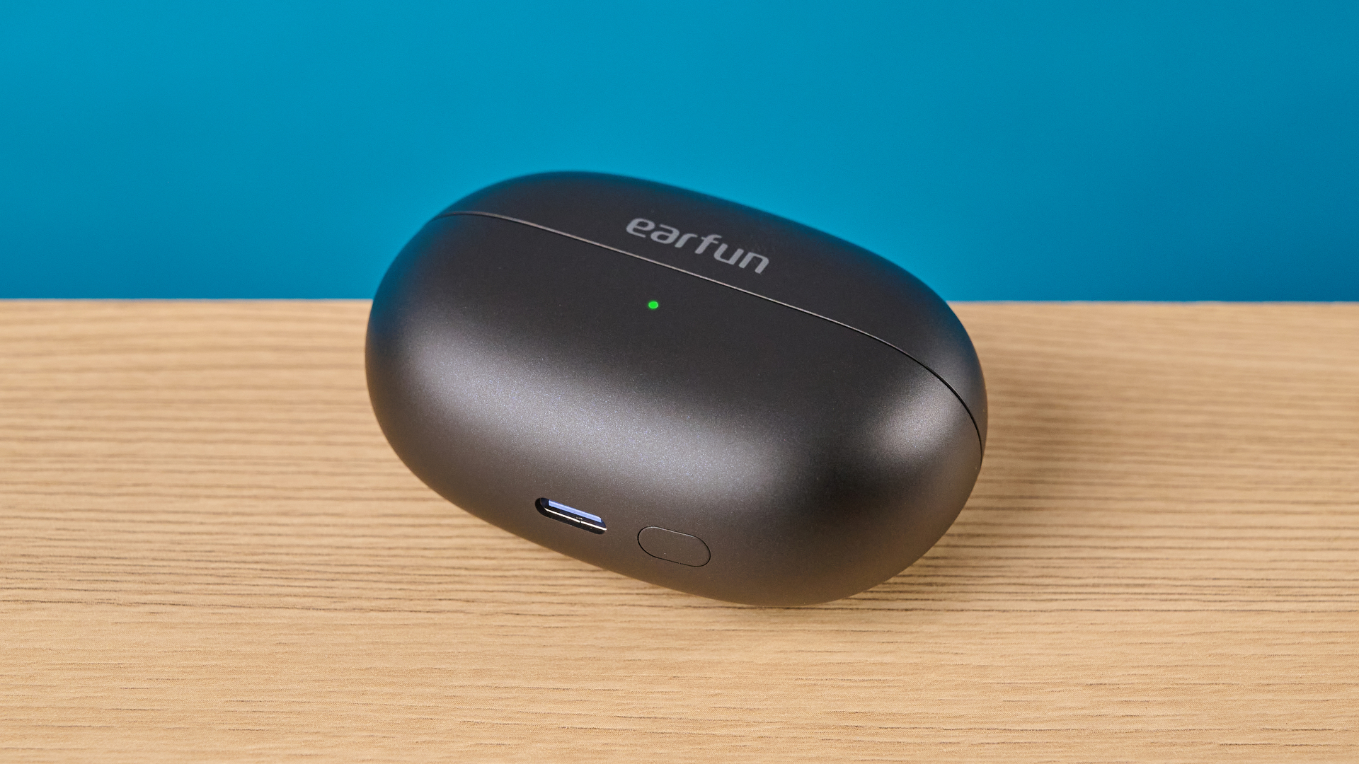 EarFun Clip 2 בשחור על שולחן מצולם מול רקע כחול