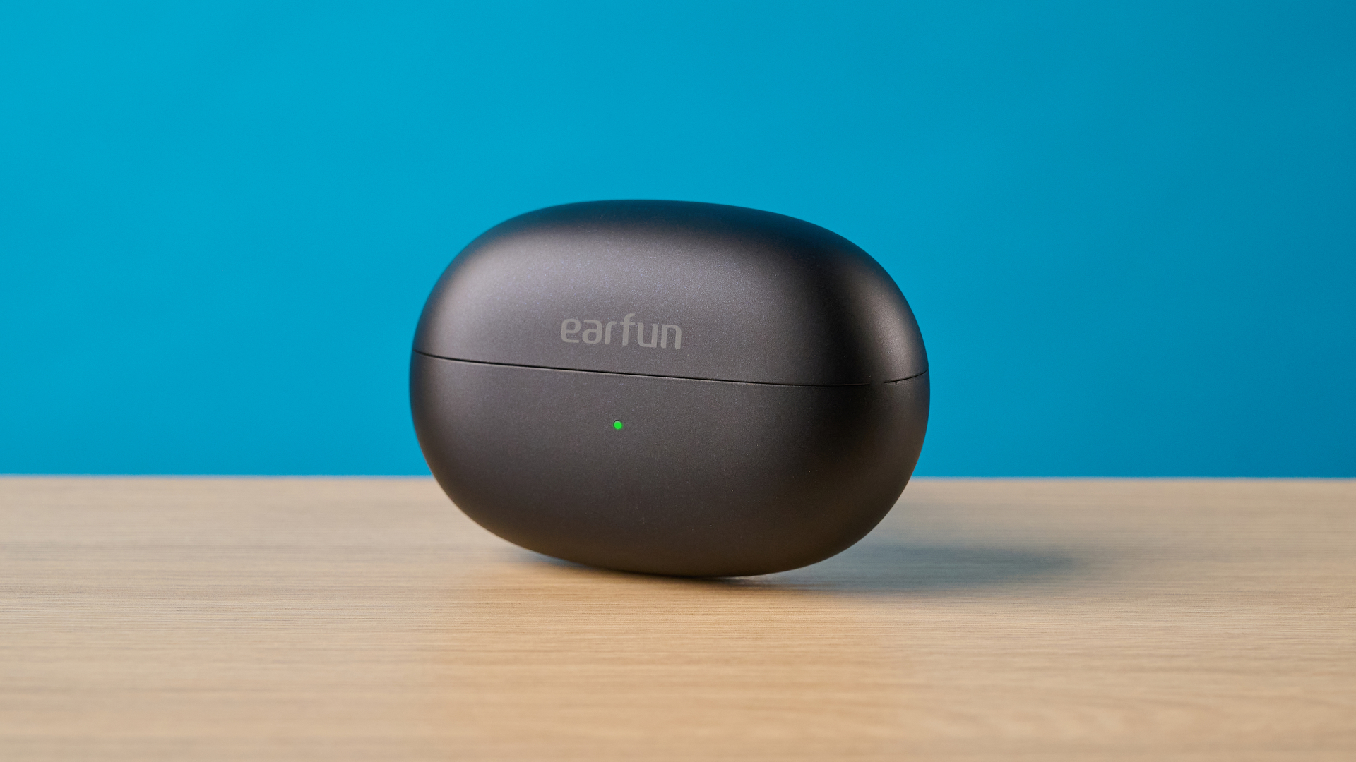 EarFun Clip 2 בשחור על שולחן מצולם מול רקע כחול