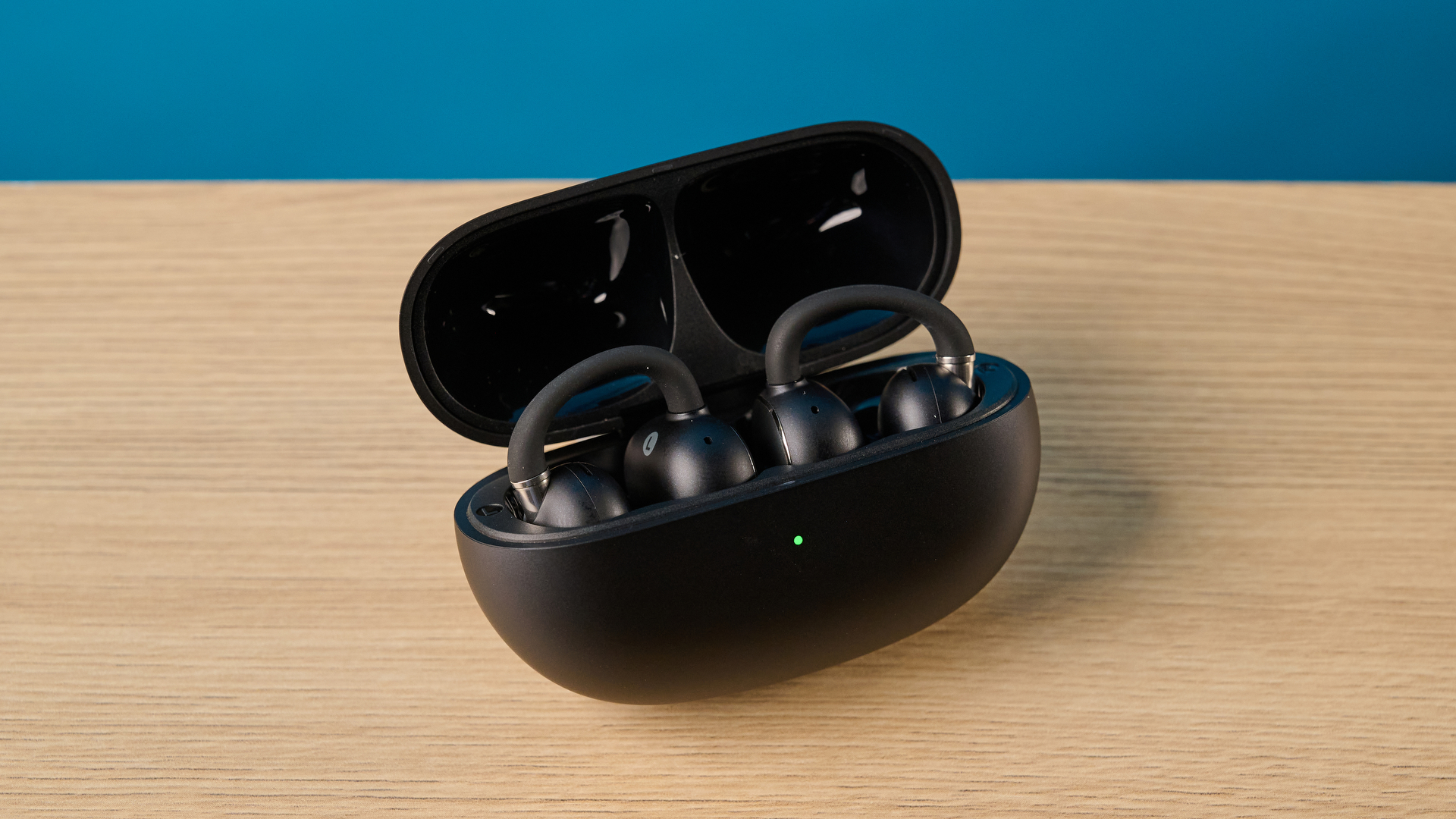 EarFun Clip 2 בשחור על שולחן מצולם מול רקע כחול