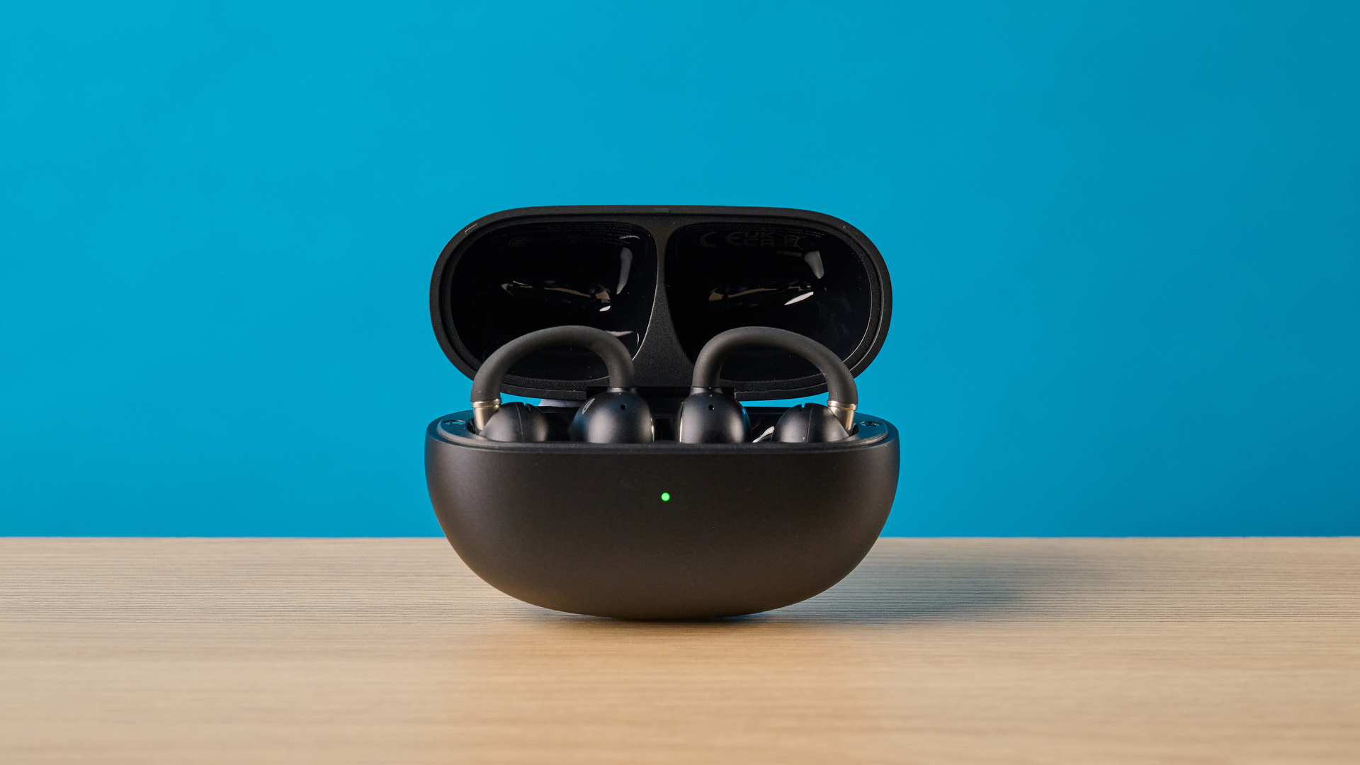 EarFun Clip 2 בשחור על שולחן מצולם מול רקע כחול