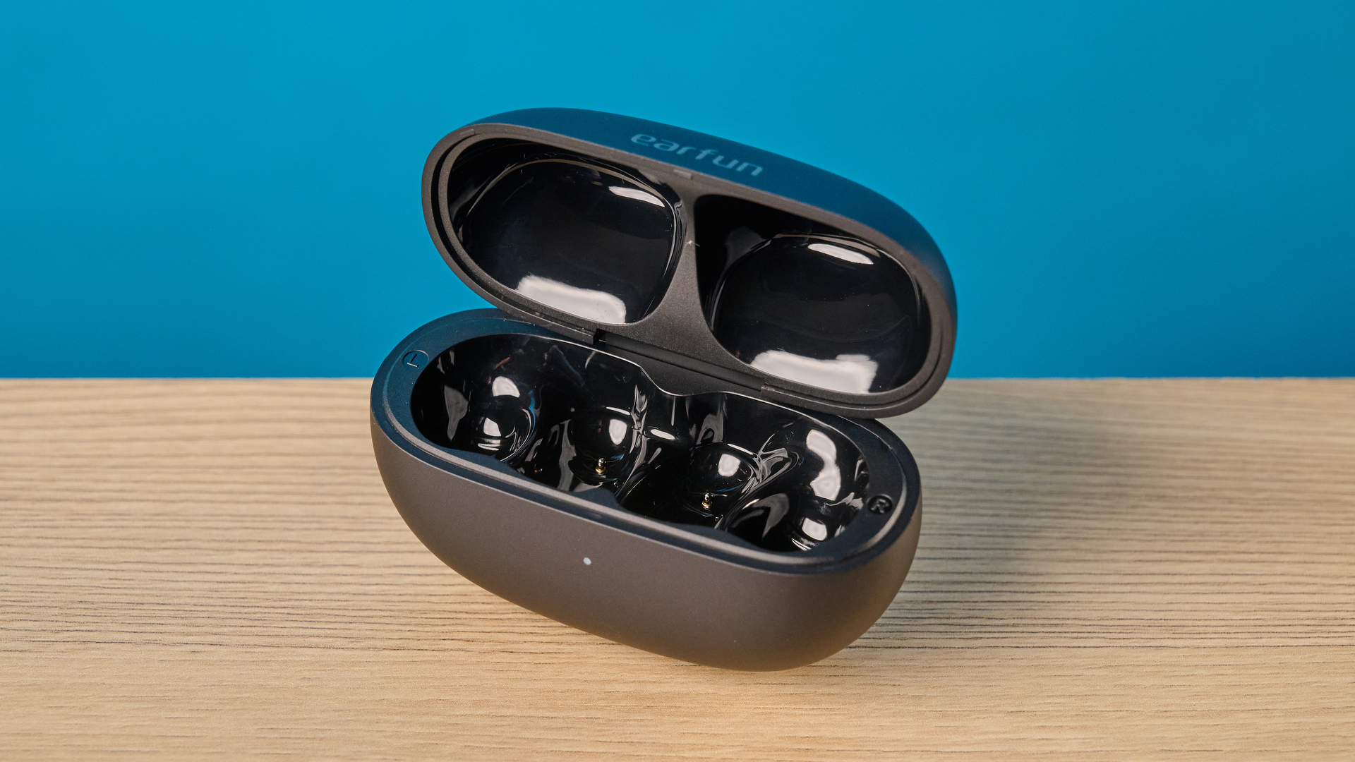 EarFun Clip 2 בשחור על שולחן מצולם מול רקע כחול