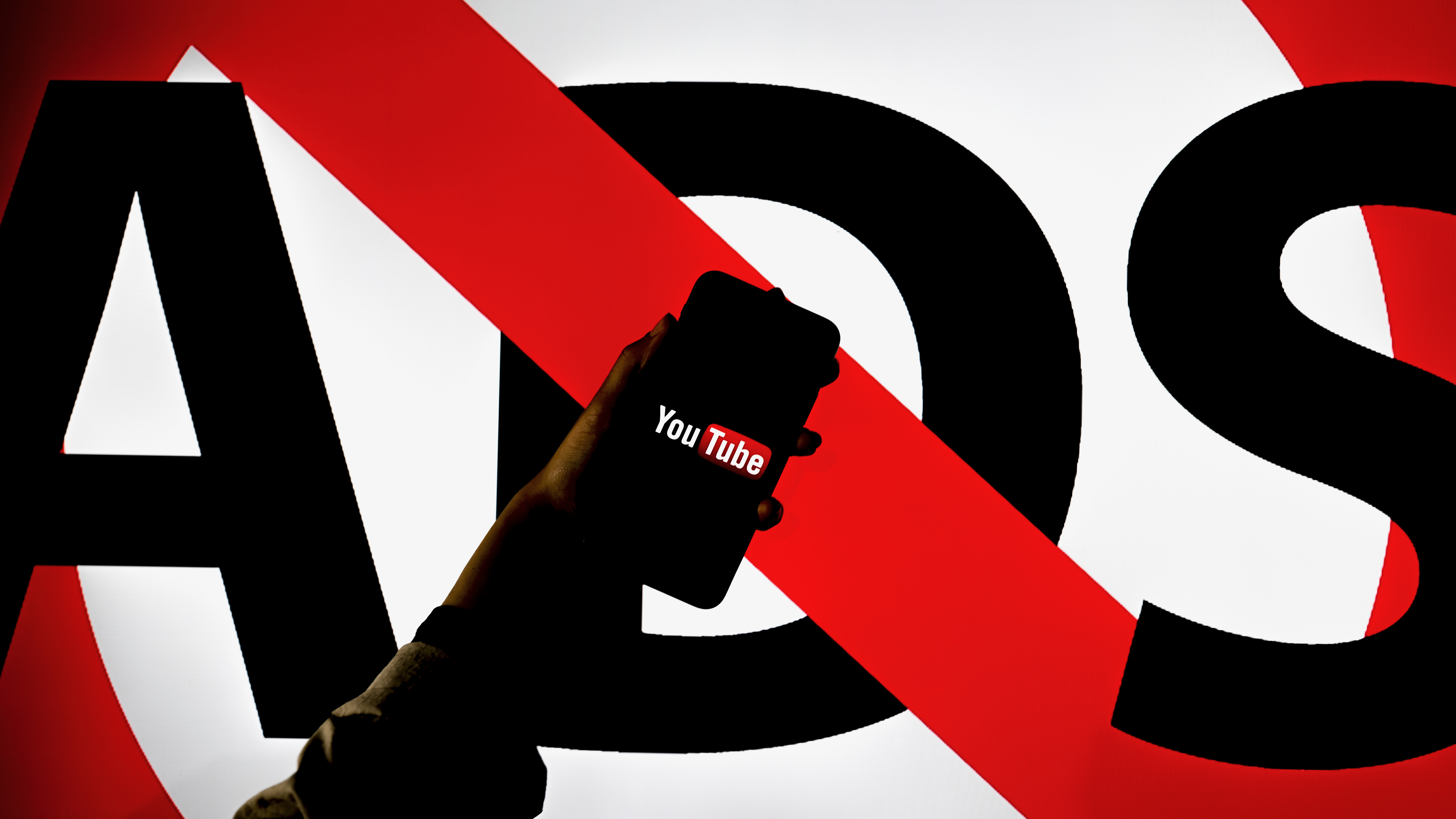 שלט גדול עם המילה "ADS" מחוצה החוצה, כשסמארטפון מציג את אפליקציית YouTube לפניו.