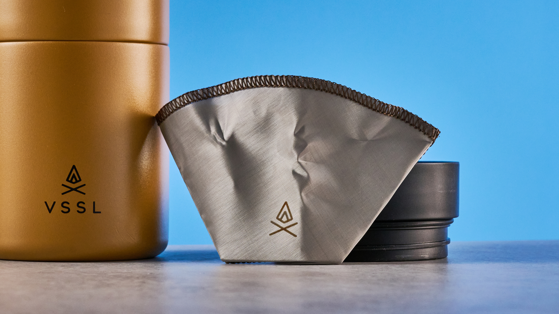 סט VSSL Nest Pour Over Coffee בזהב שצולם על רקע המדריך הכחול