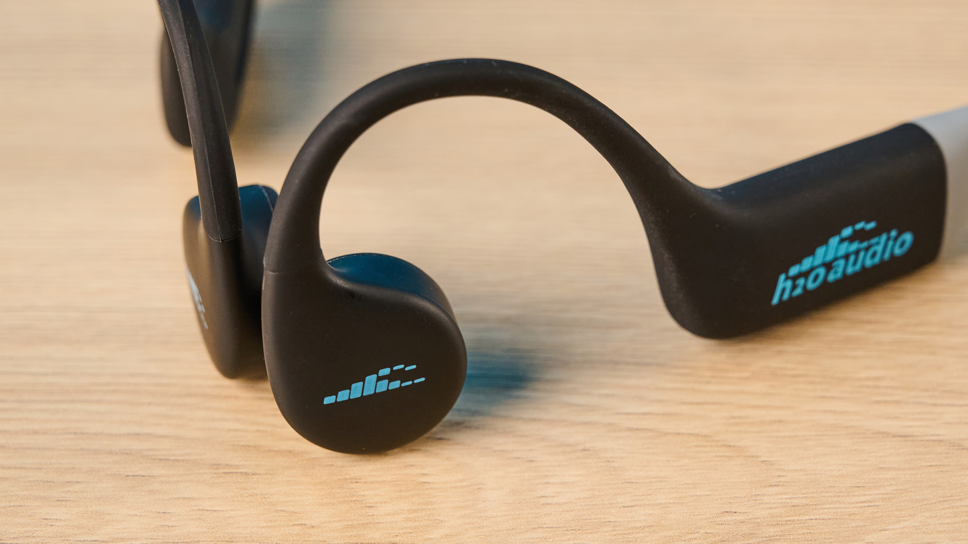אוזניות ה-h2o audio tri run bone conduction שצולמו על רקע כחול של Tom's guide
