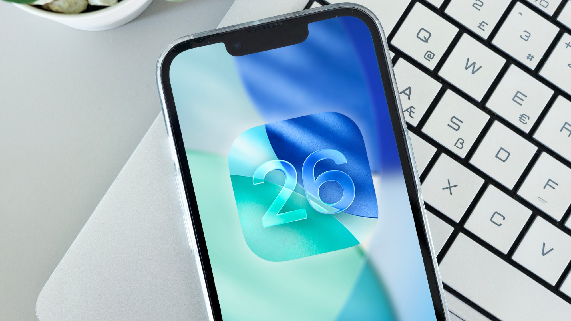 לוגו iOS 26 באייפון יושב על מקלדת מחשב נייד