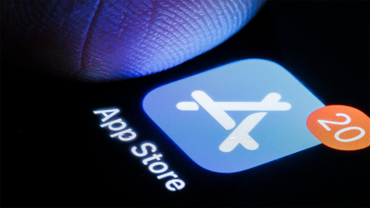 סמל Apple App Store מוצג באייפון עם סמל התראה ותקריב של אצבע של אדם