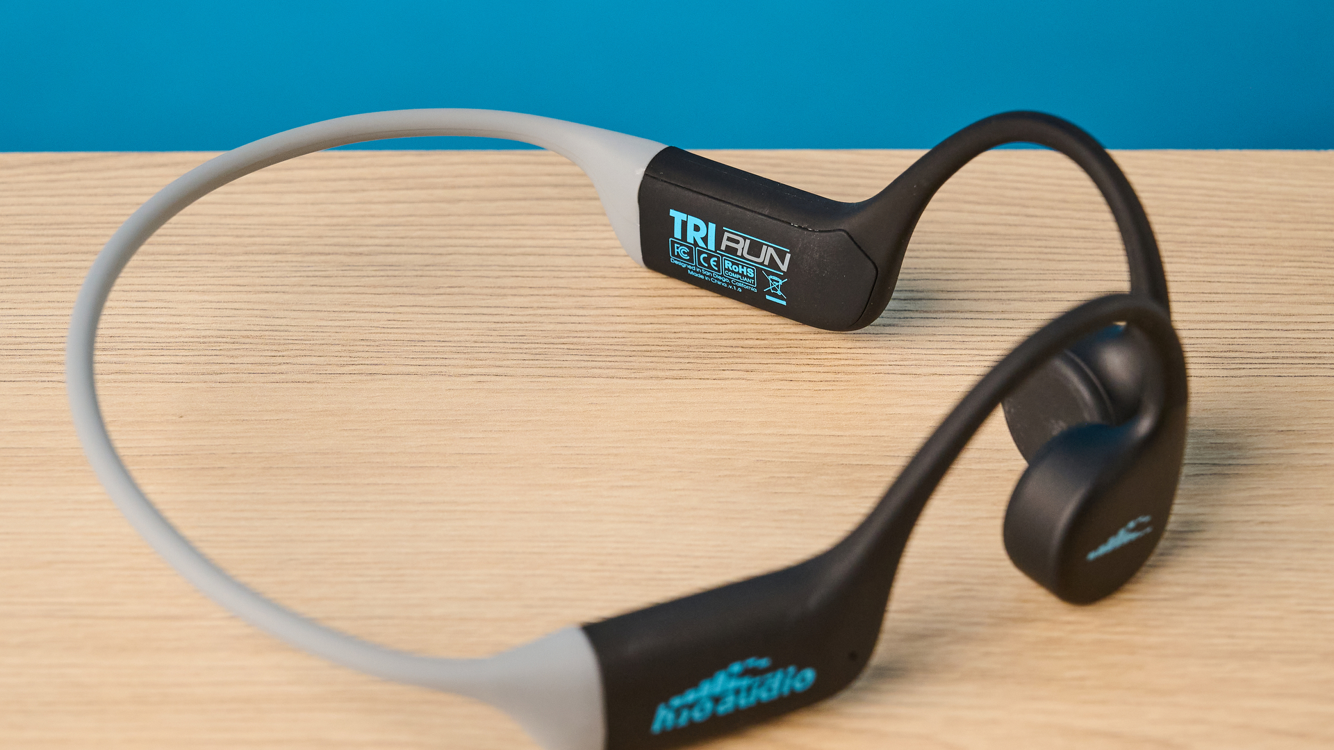 אוזניות ה-h2o audio tri run bone conduction שצולמו על רקע כחול של Tom's guide