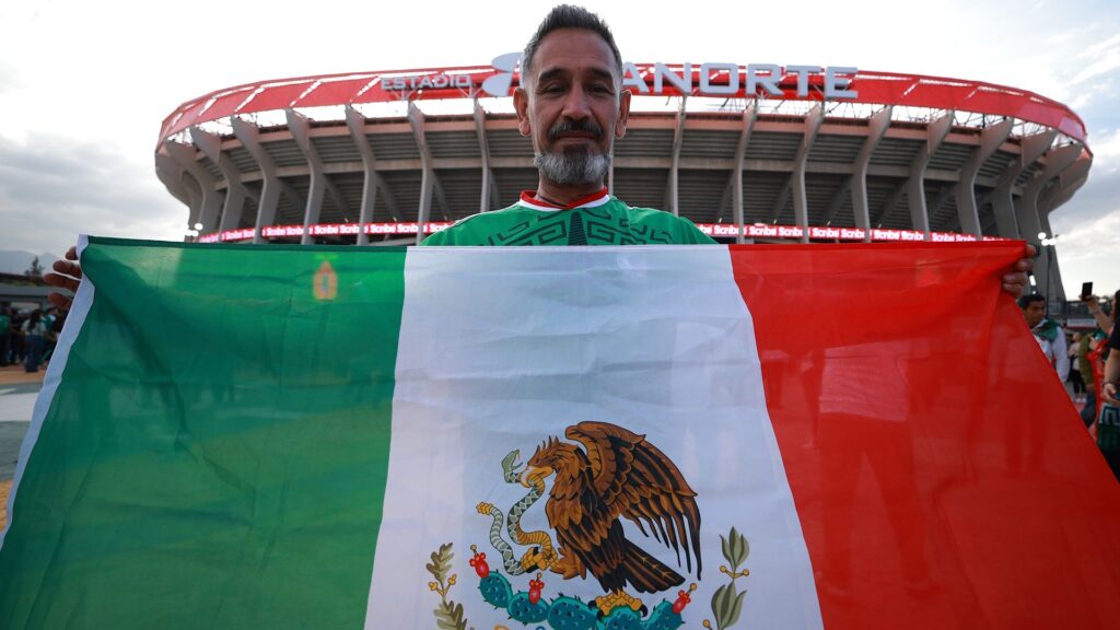 A fan shows a flag of Mexico outside the Estadio Azteca.