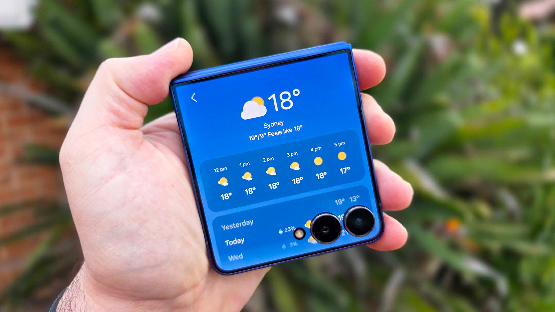 תמונה ביד של Samsung Galaxy Z Flip 7 עם גינה ברקע