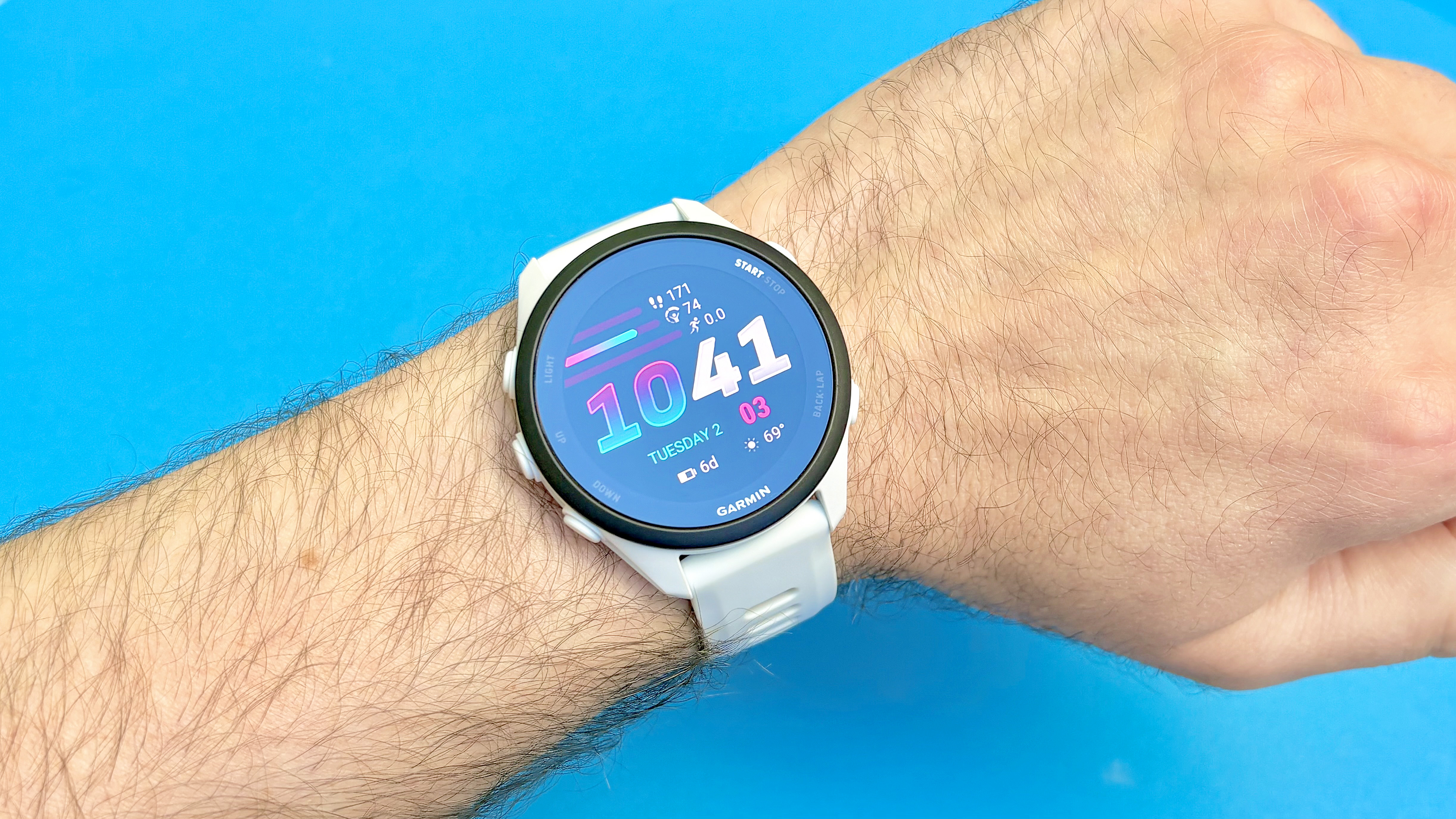 תקריב של Garmin Forerunner 70 על פרק כף היד של משתמש על רקע כחול בהיר