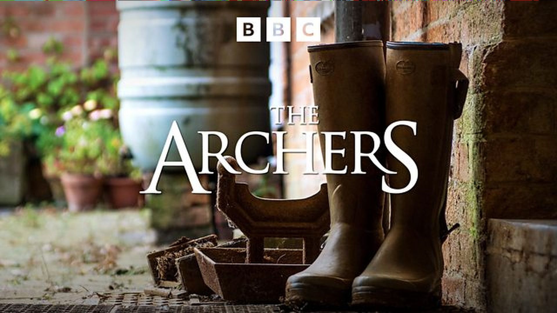 Promotional title card for "The Archers" featuring the title displayed over a pair of wellington boots in a rural English setting