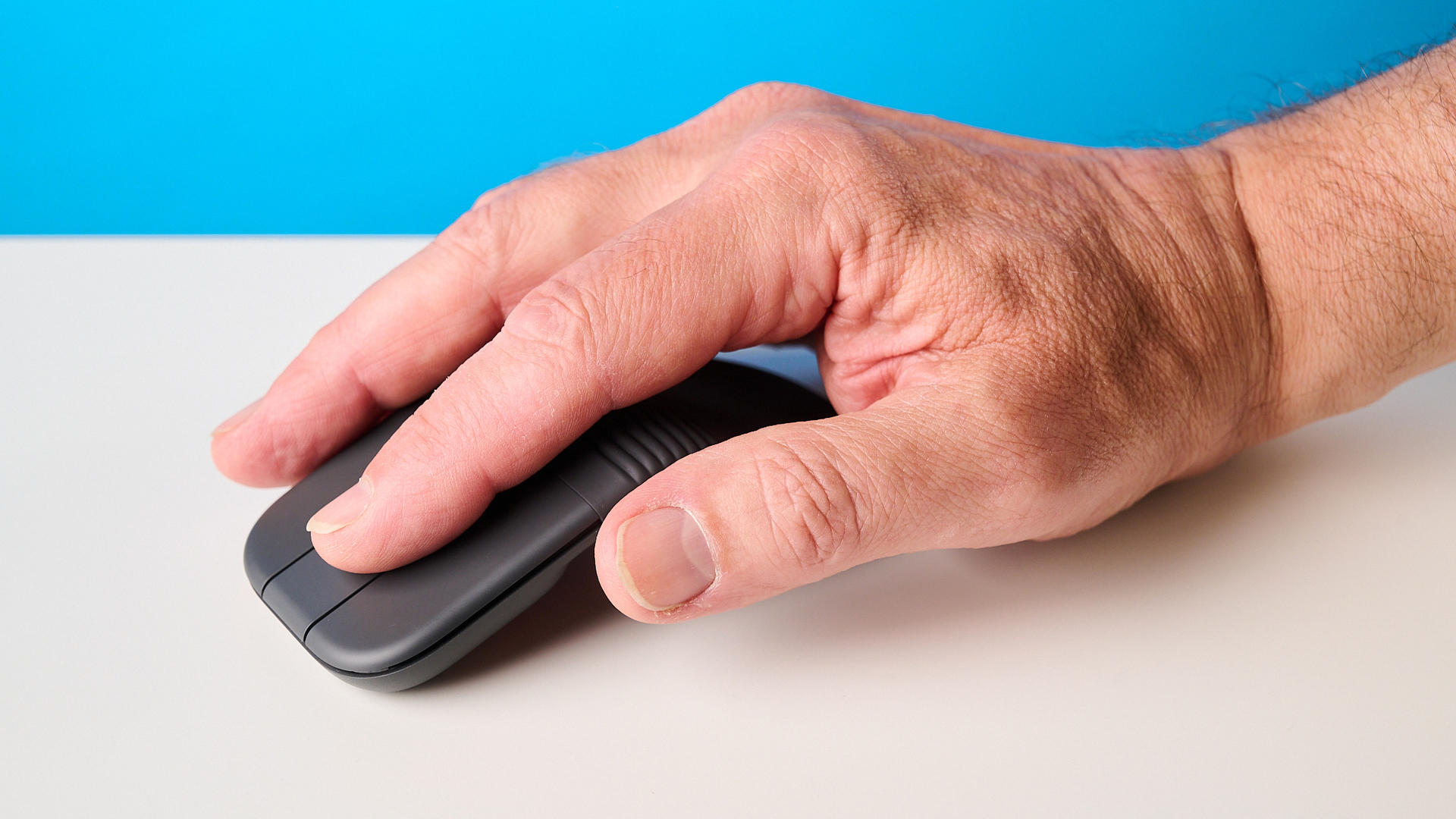 עכבר Logitech Mobi Fold בגרפיט מצולם מול רקע כחול
